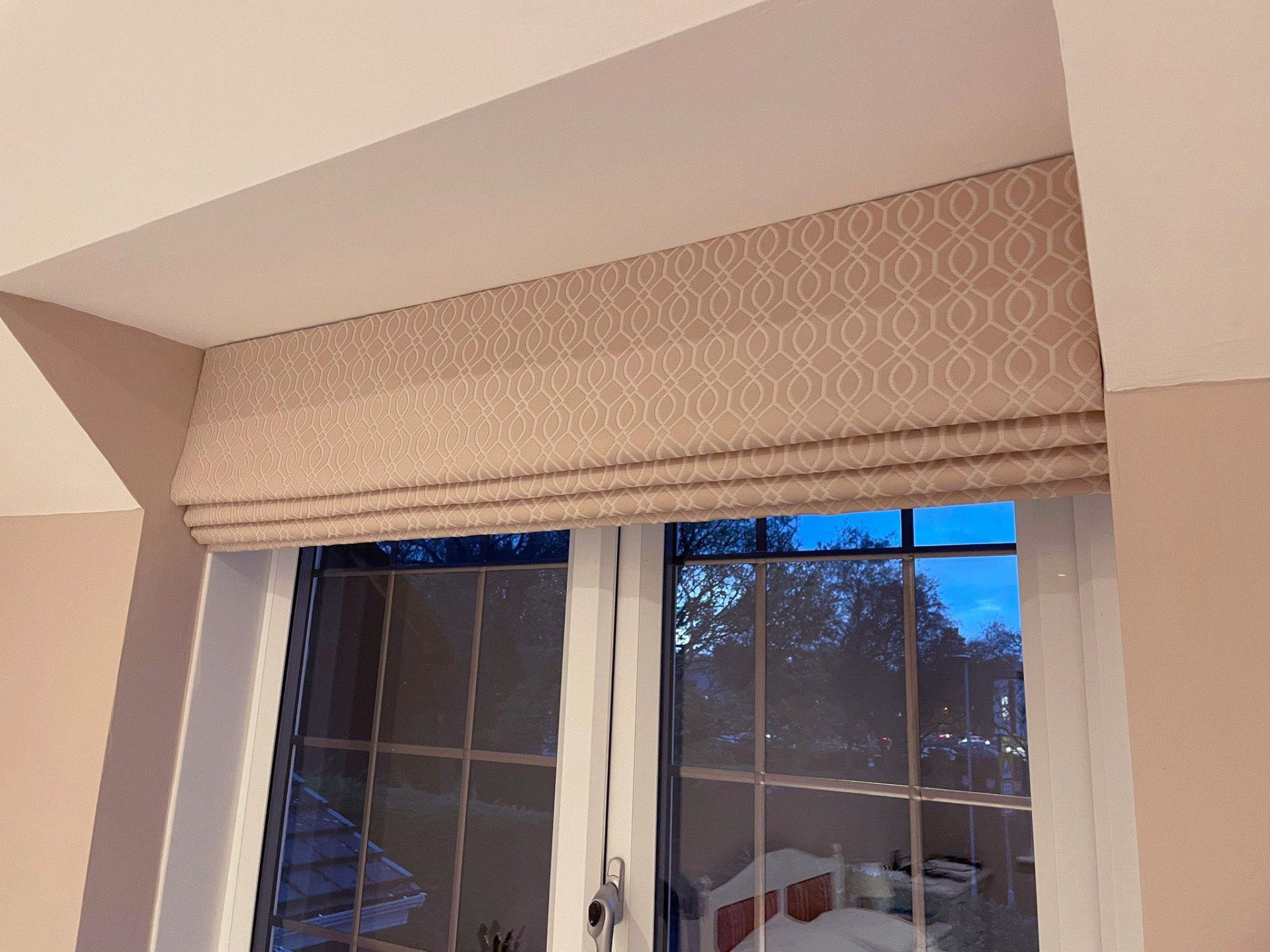 A window with a roman shade on it in a bedroom.