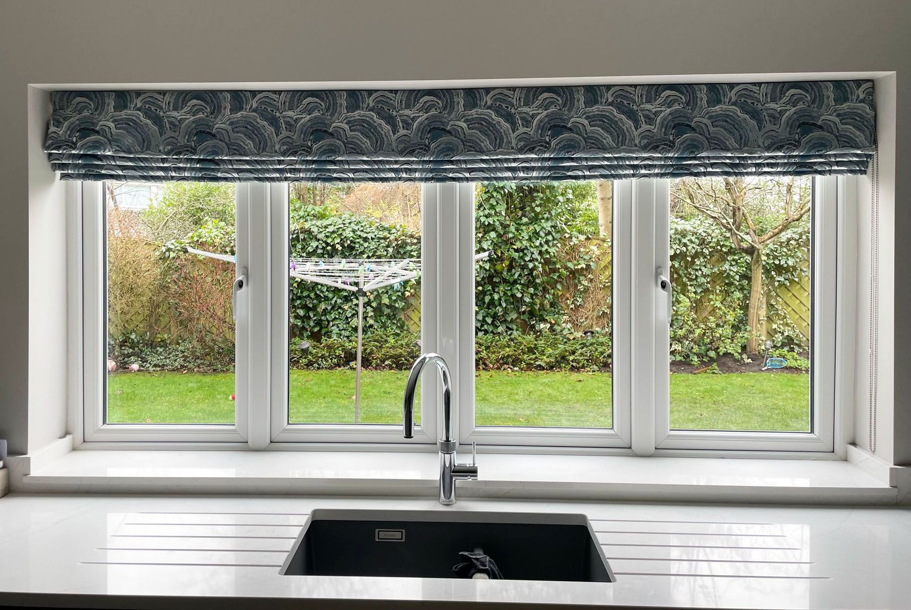 A kitchen with a sink and a window with a blind on it.