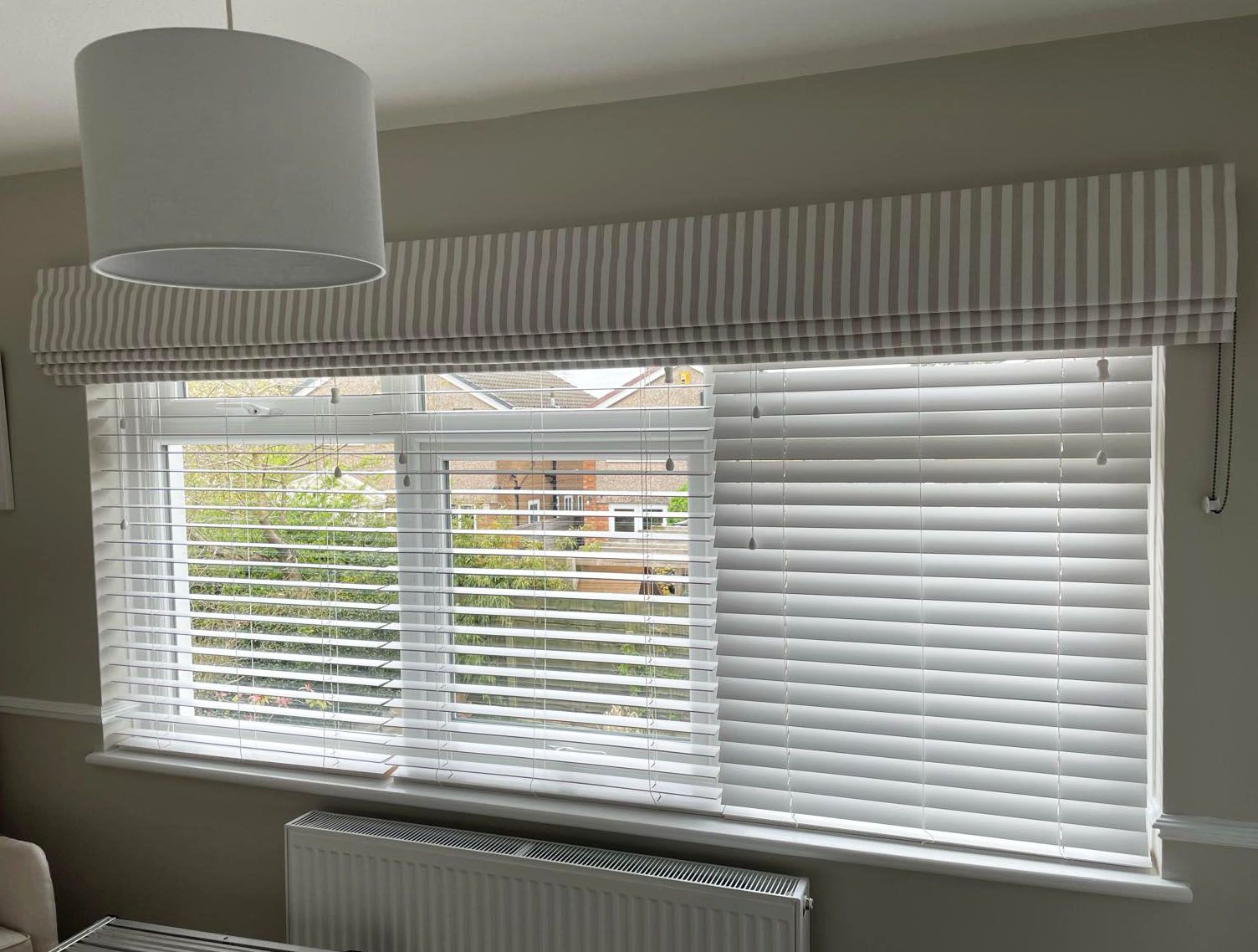 A living room with a large window with blinds and a striped valance.