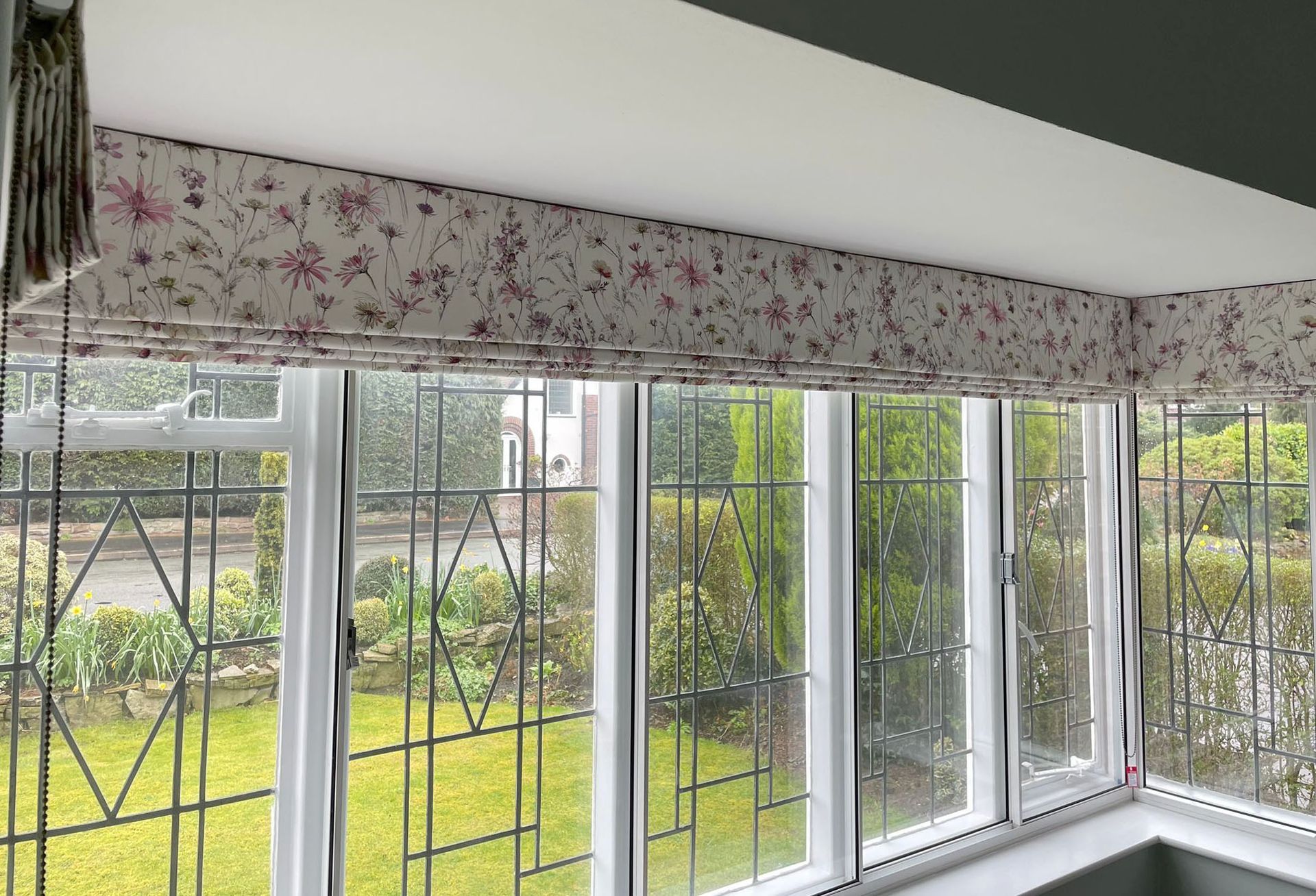 A room with a lot of windows and a floral curtain on the window.