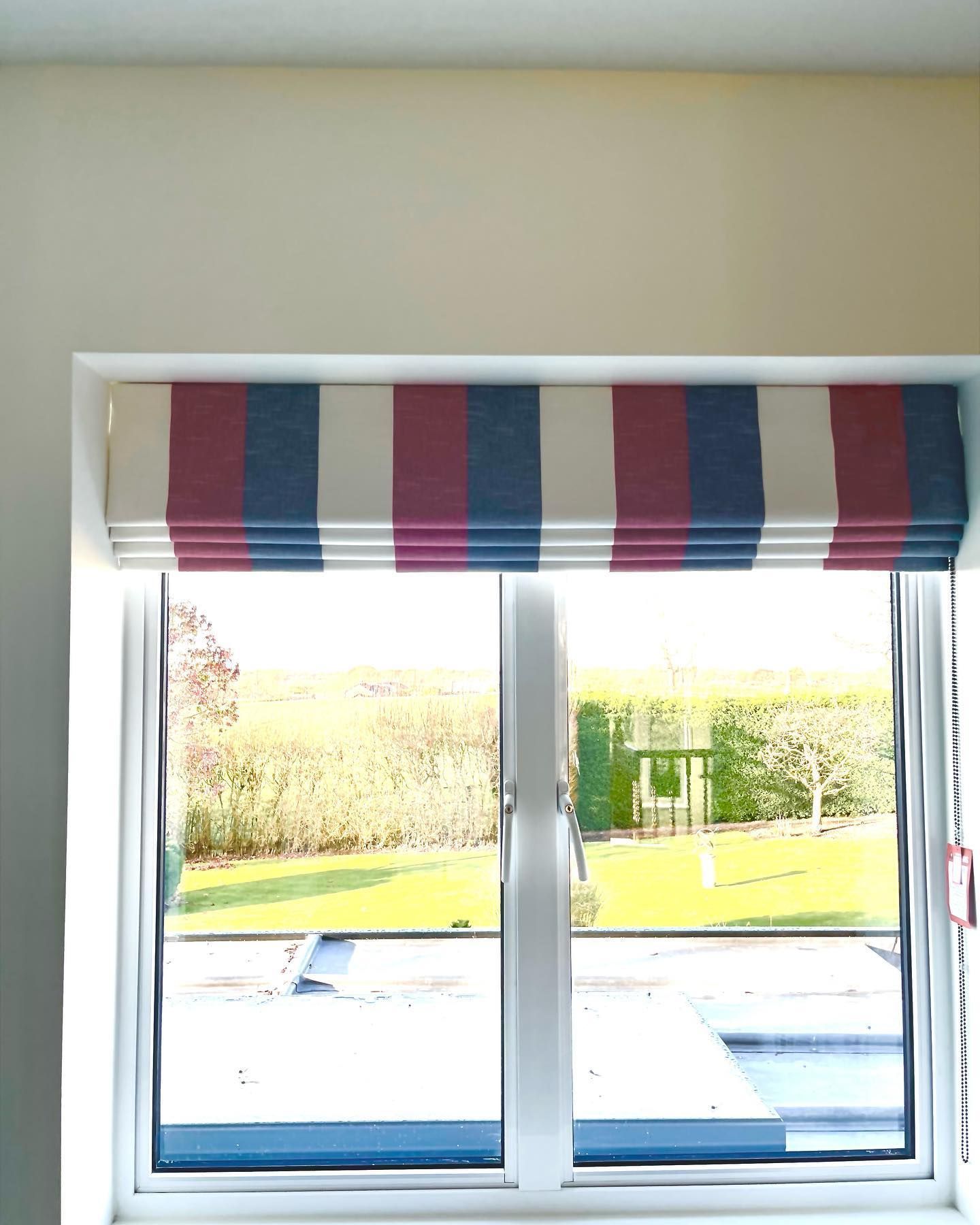 A window with a red , white and blue striped blind on it