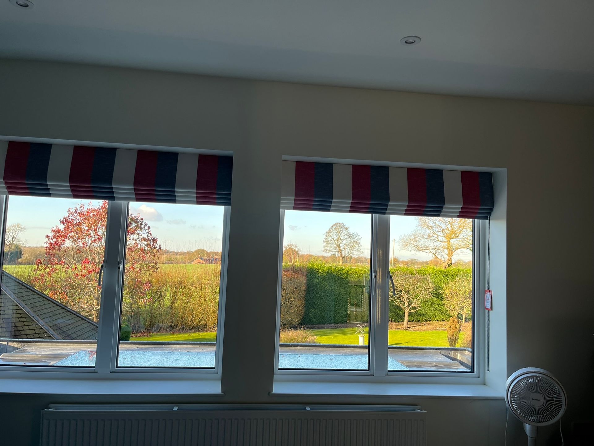 A room with two windows with red and white striped blinds