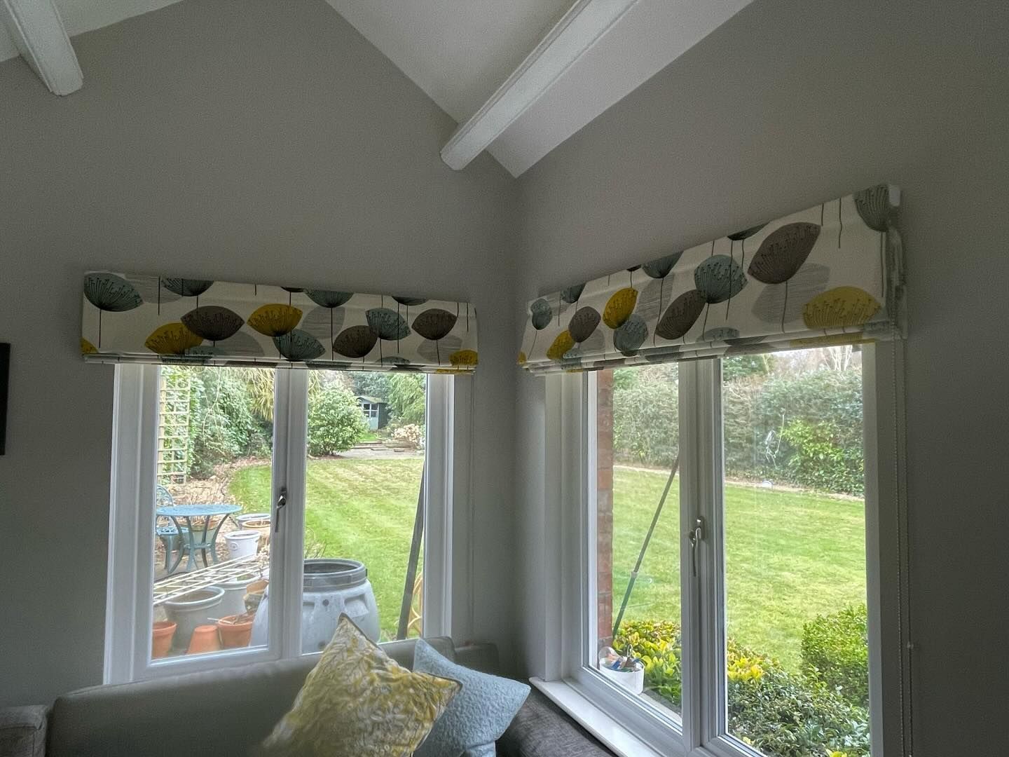 A living room with a couch and two windows with curtains on them.