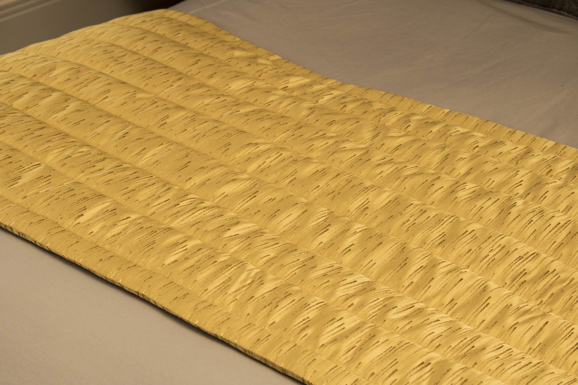 A yellow quilted bed runner