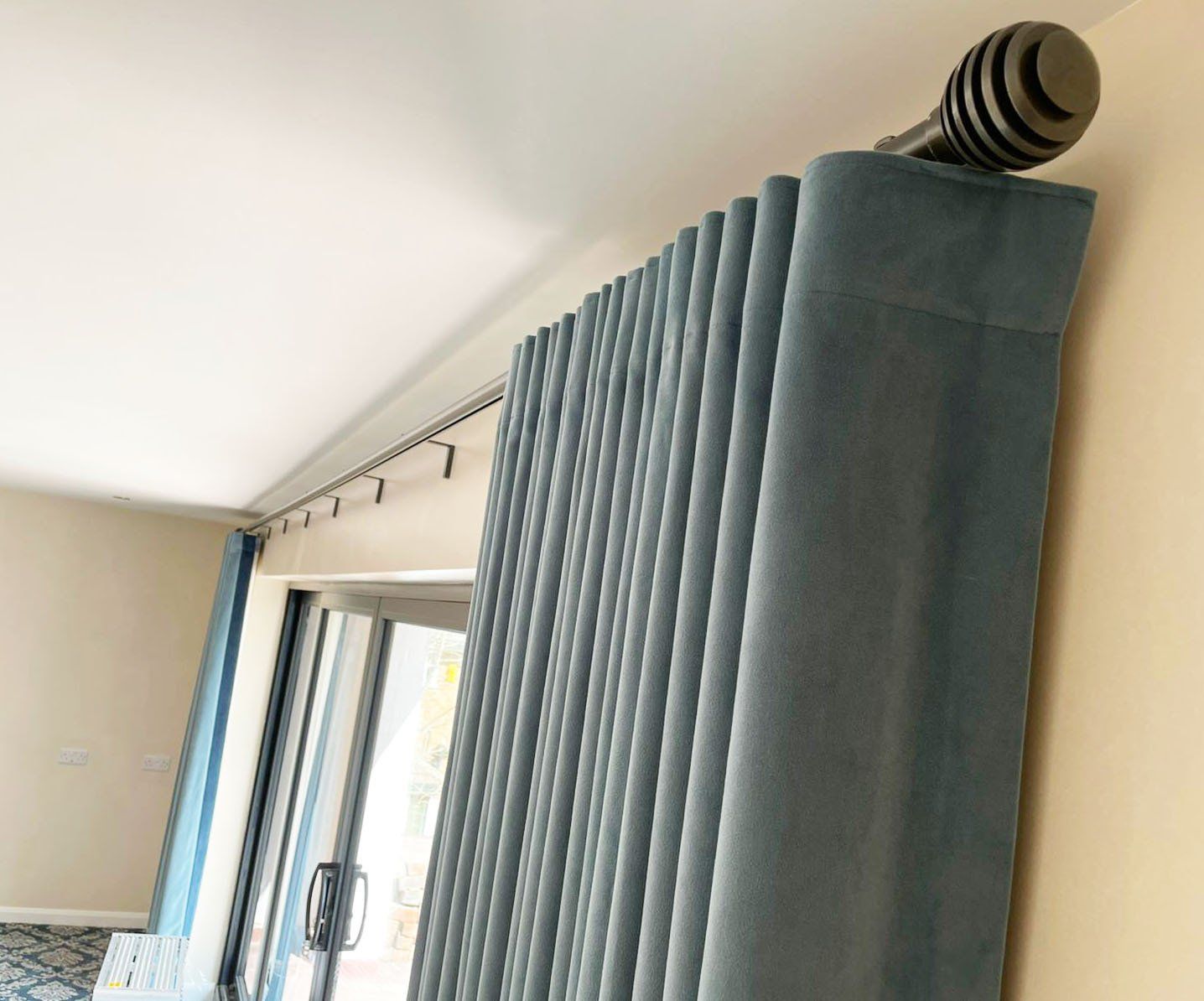 A pair of blue curtains are hanging from the ceiling in a living room.