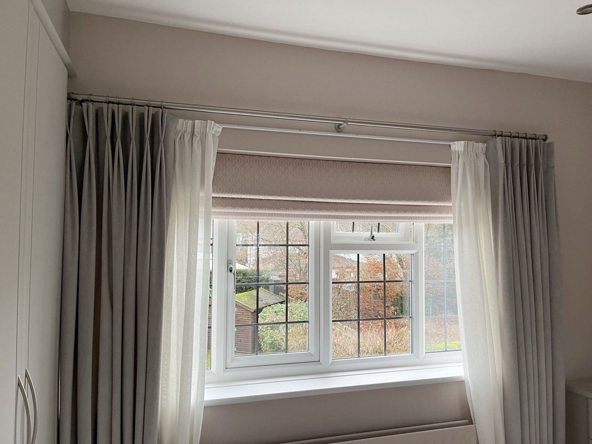 A bedroom with a large window and curtains on it.