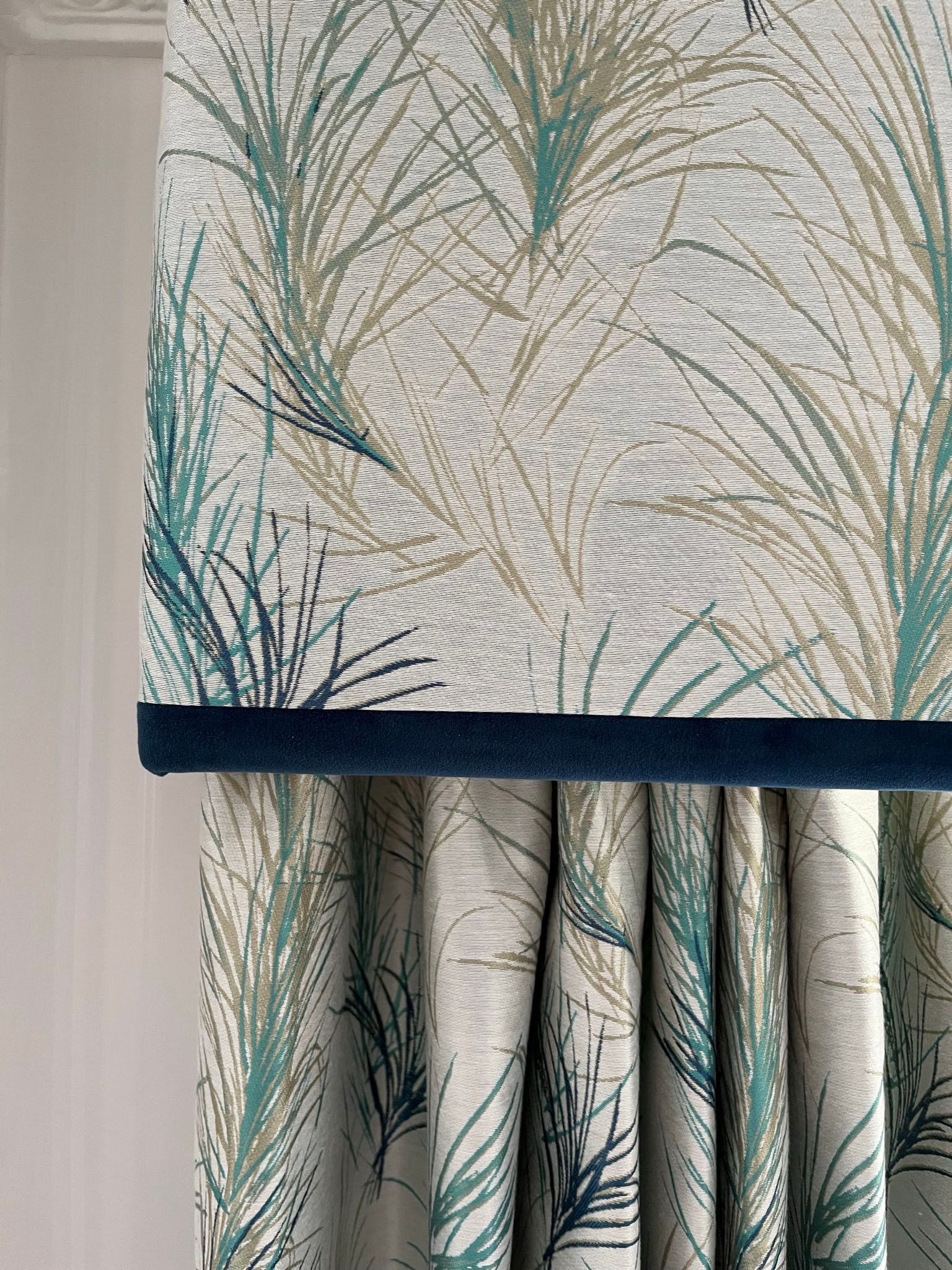 A pelmet with a peacock feather pattern and a blue trim.
