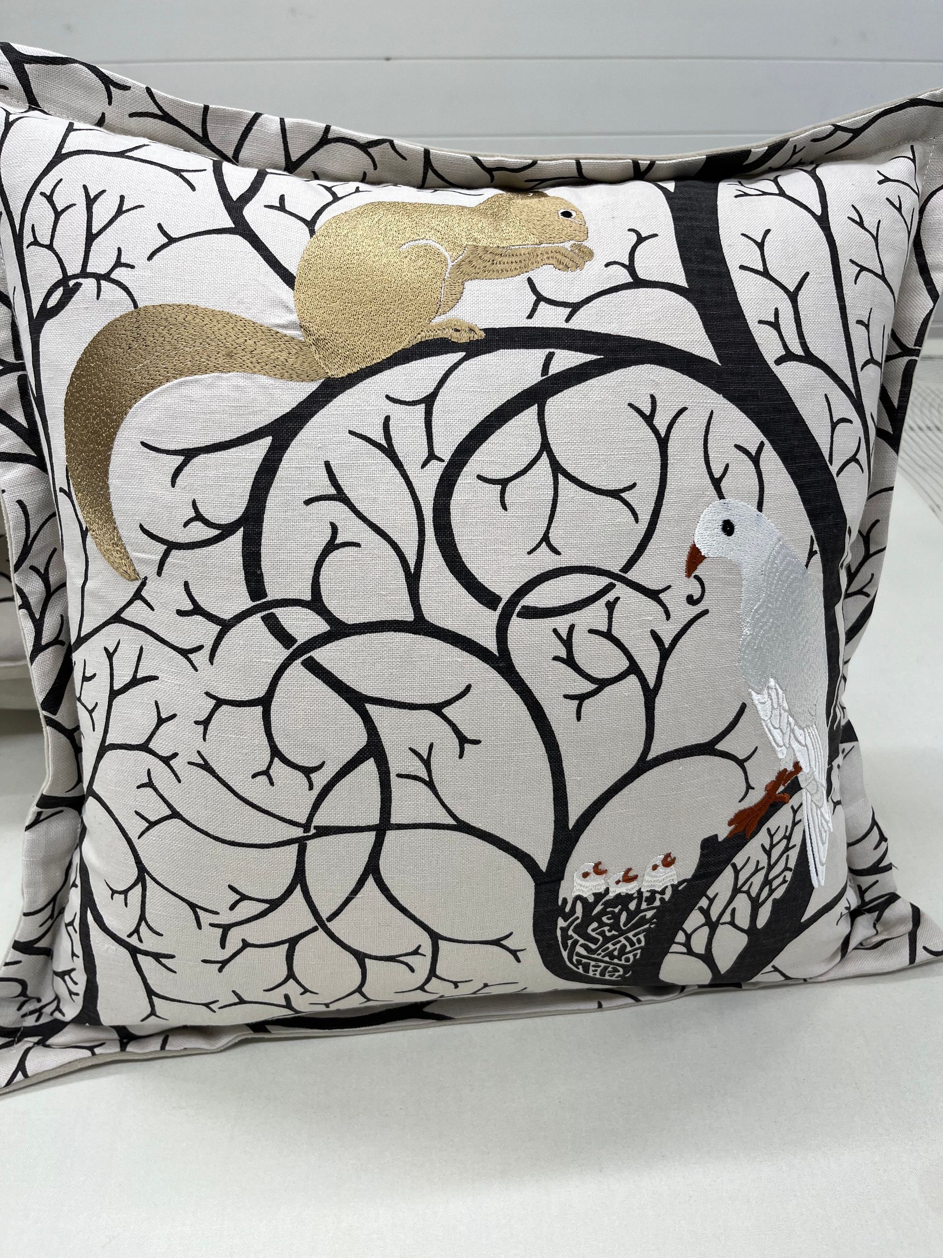 A pillow with a squirrel on it is sitting on a couch.