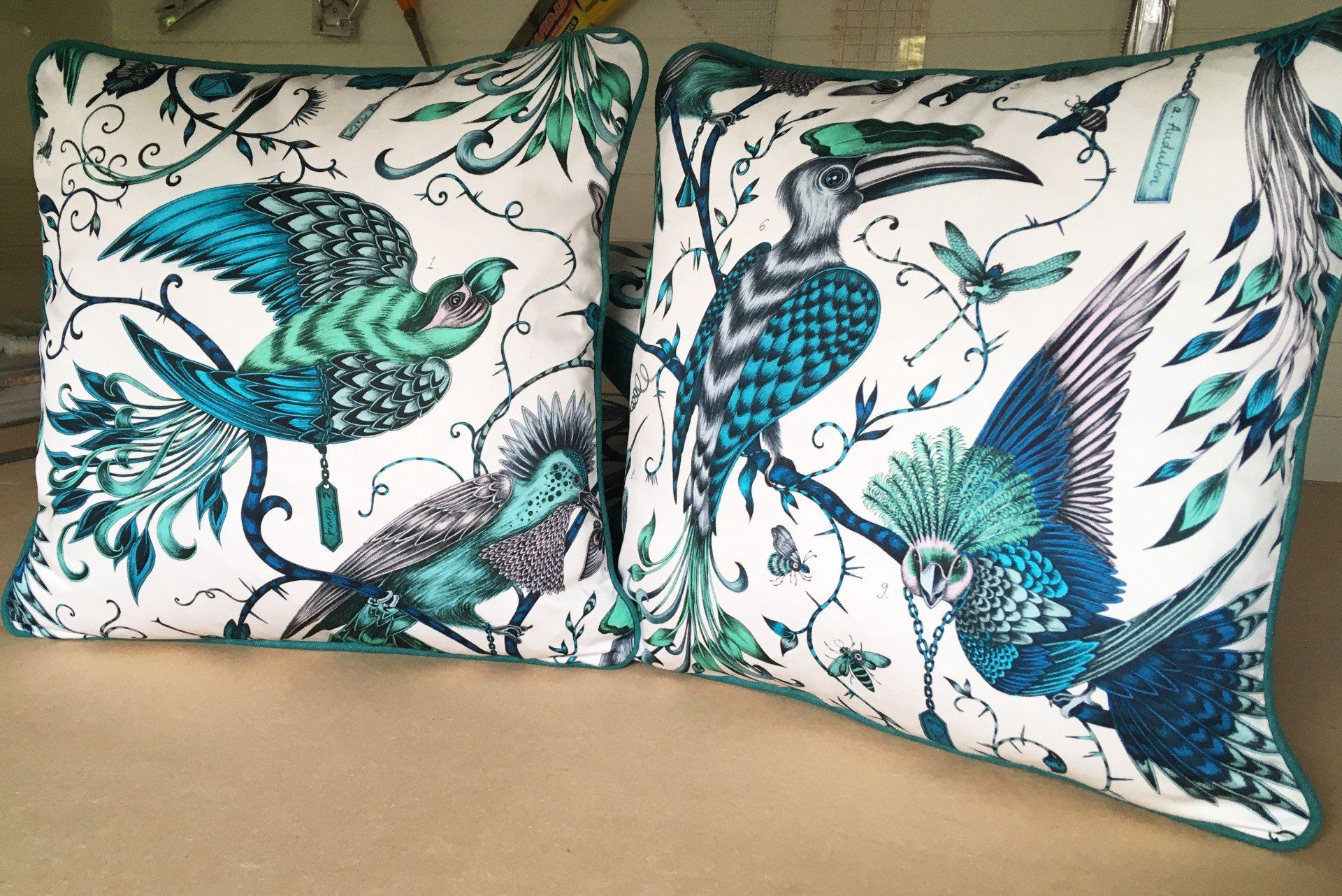 Two pillows with birds on them are sitting on a couch.