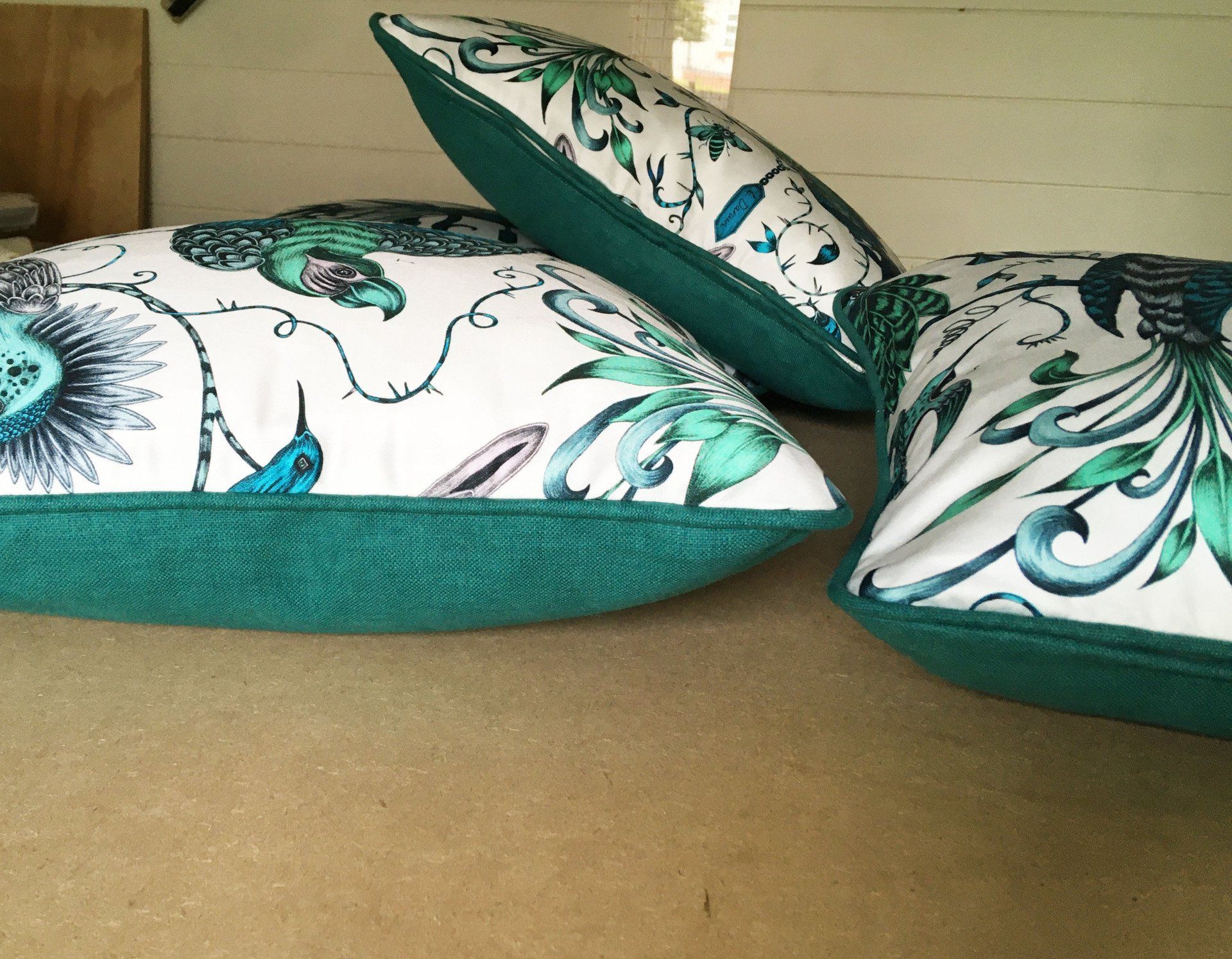 Three green and white pillows are sitting on a carpet