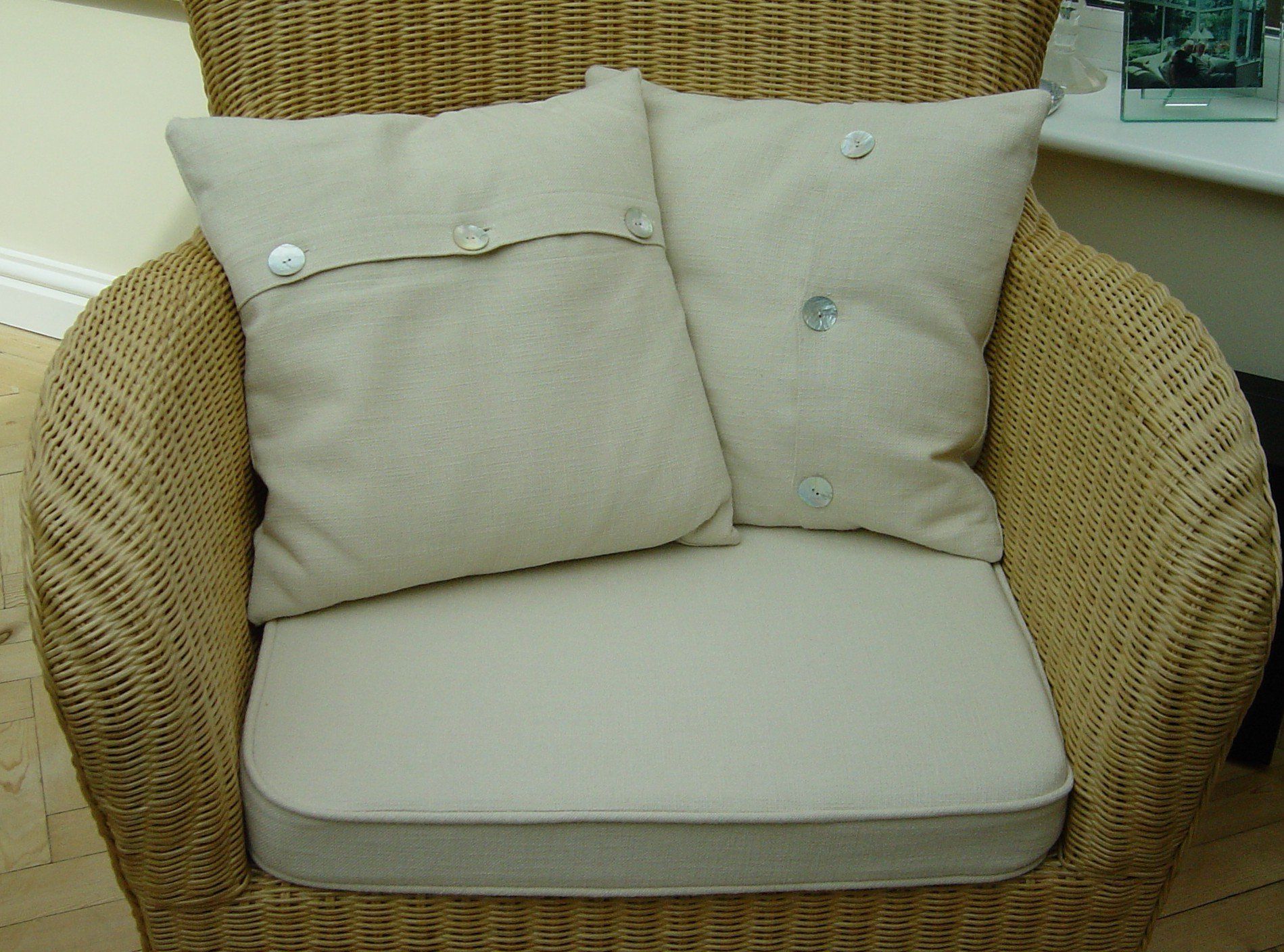 A wicker chair with two pillows on it