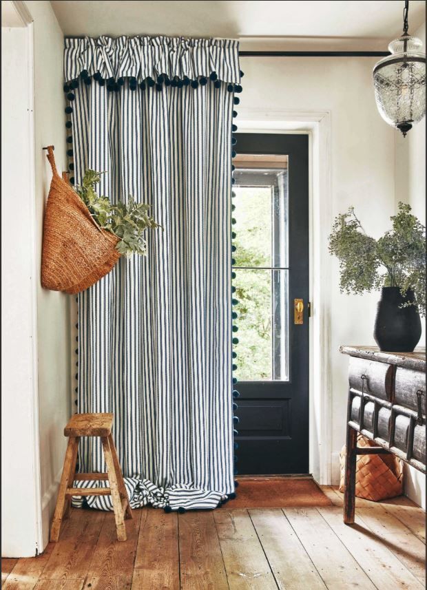 A hallway with a striped curtain and a black door.