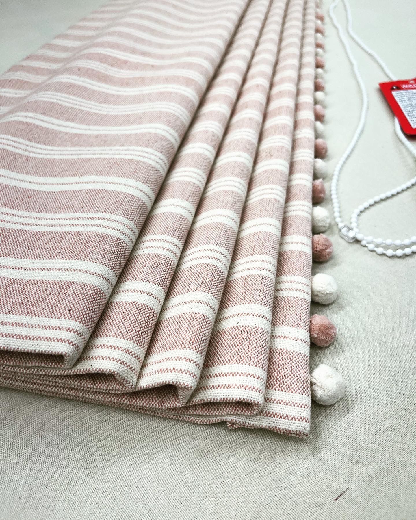 A close up of a striped fabric with pom poms on a table.