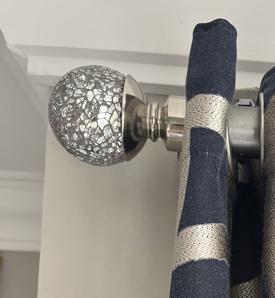 A close up of a curtain rod with a ball on it