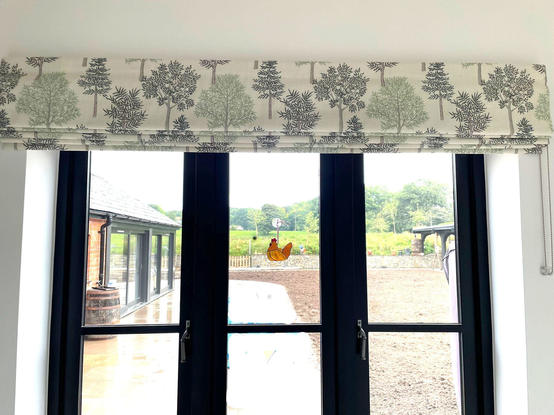 A window with a roman shade and trees on it