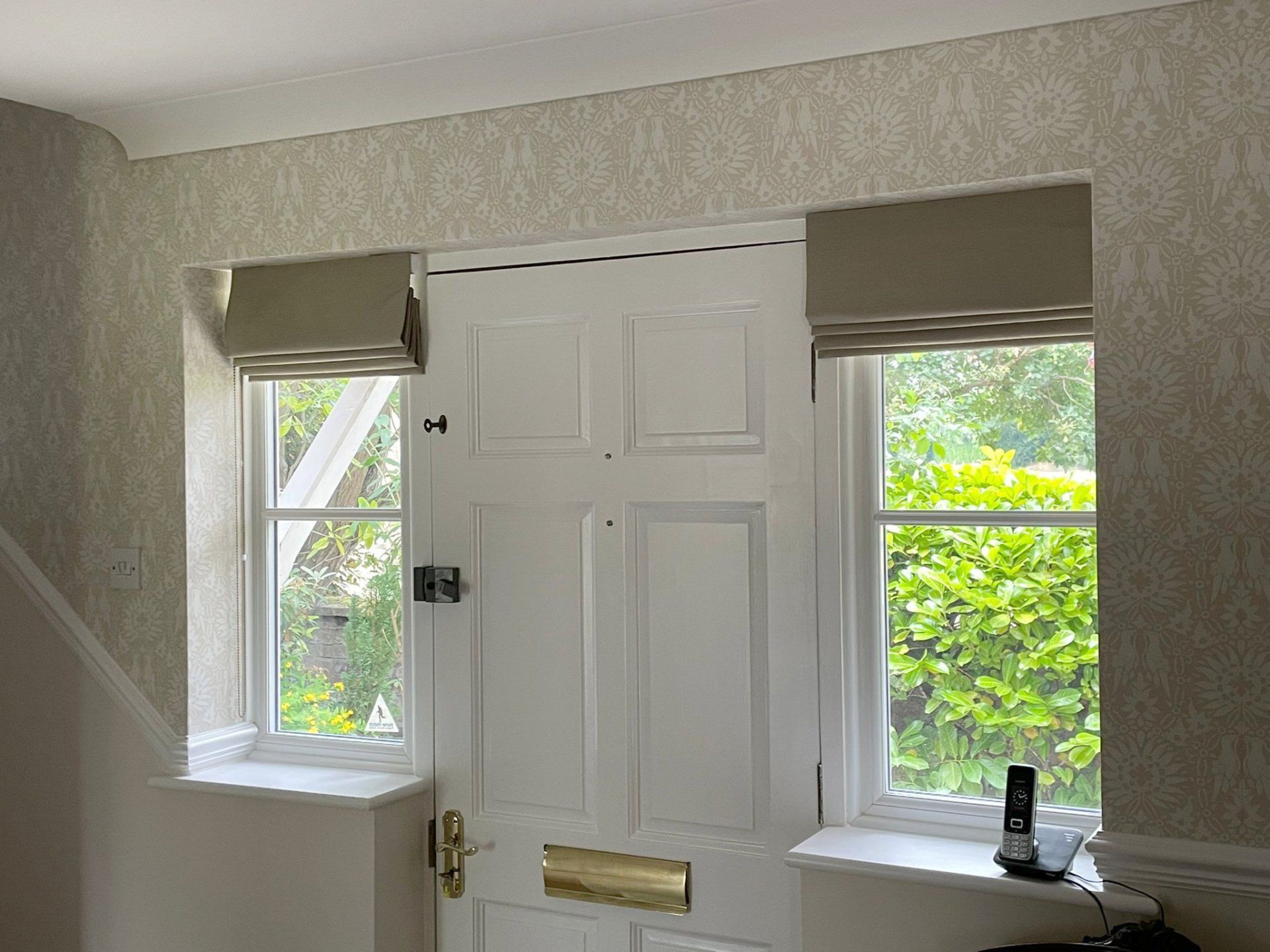 A white door with roman shades and two windows in a room.