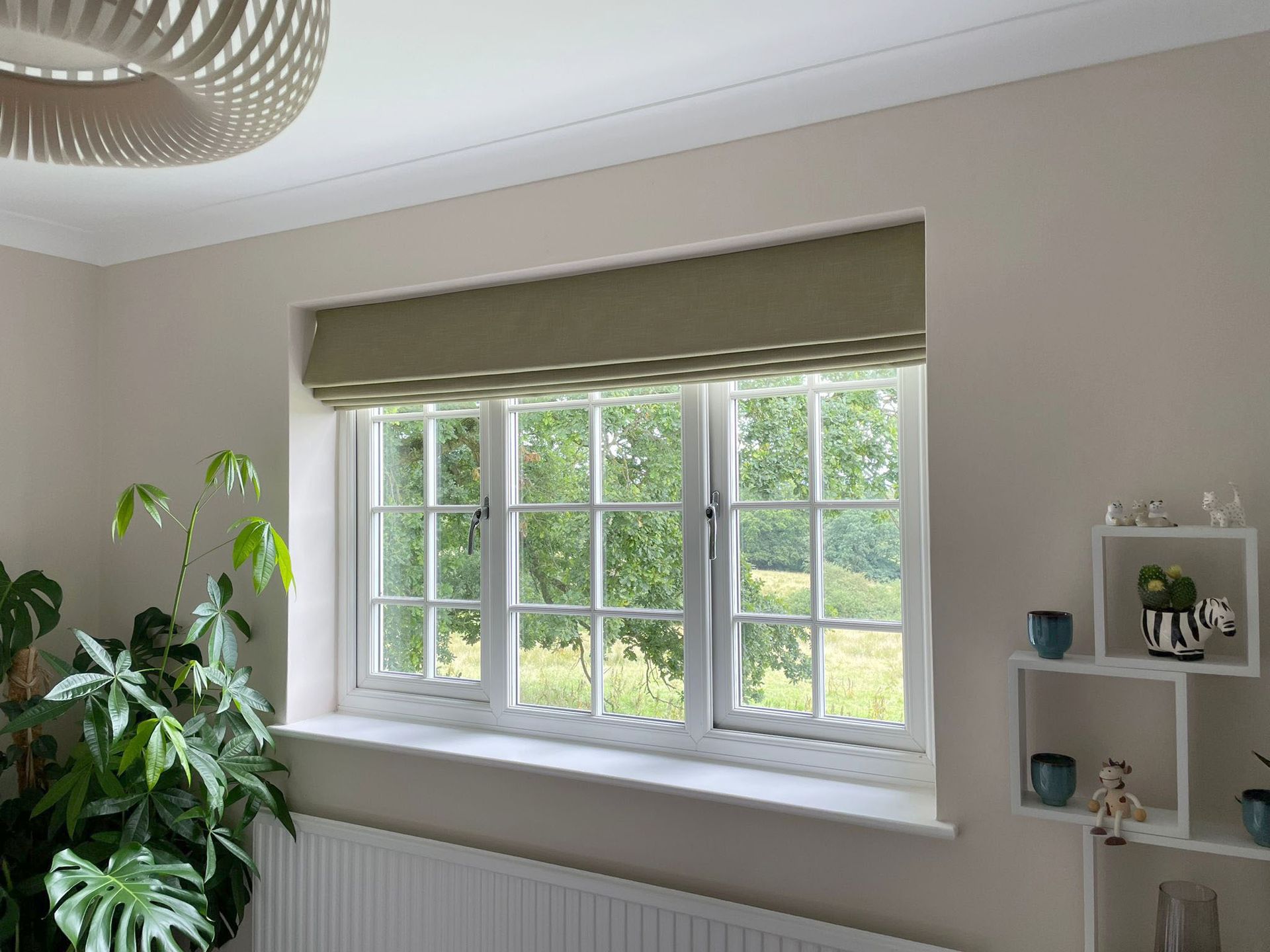A living room with a large window and a plant on the window sill.