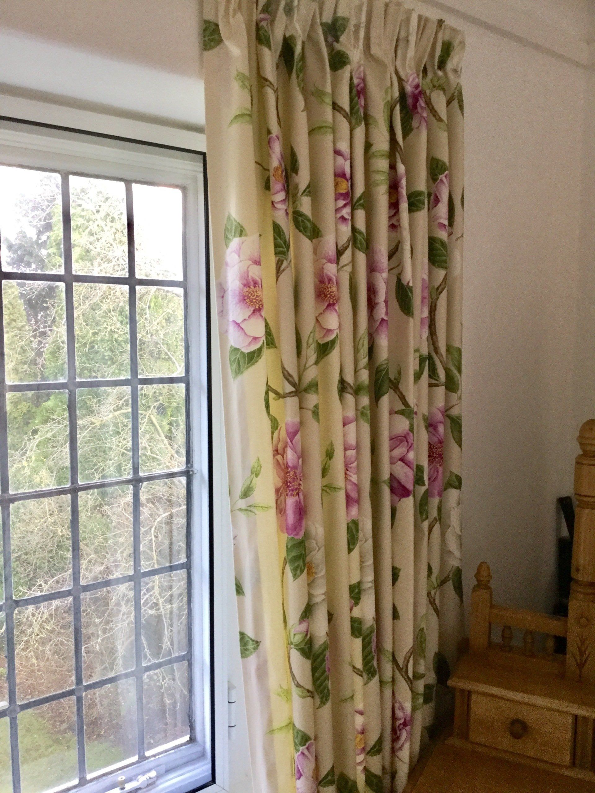 A window with a floral curtain hanging on it