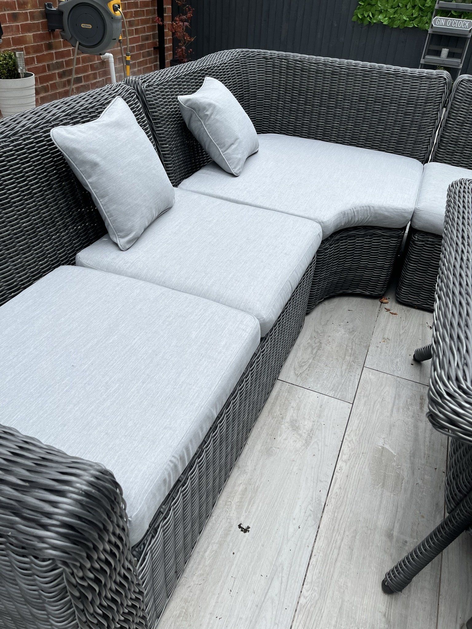 A wicker sectional couch with white cushions on a patio.