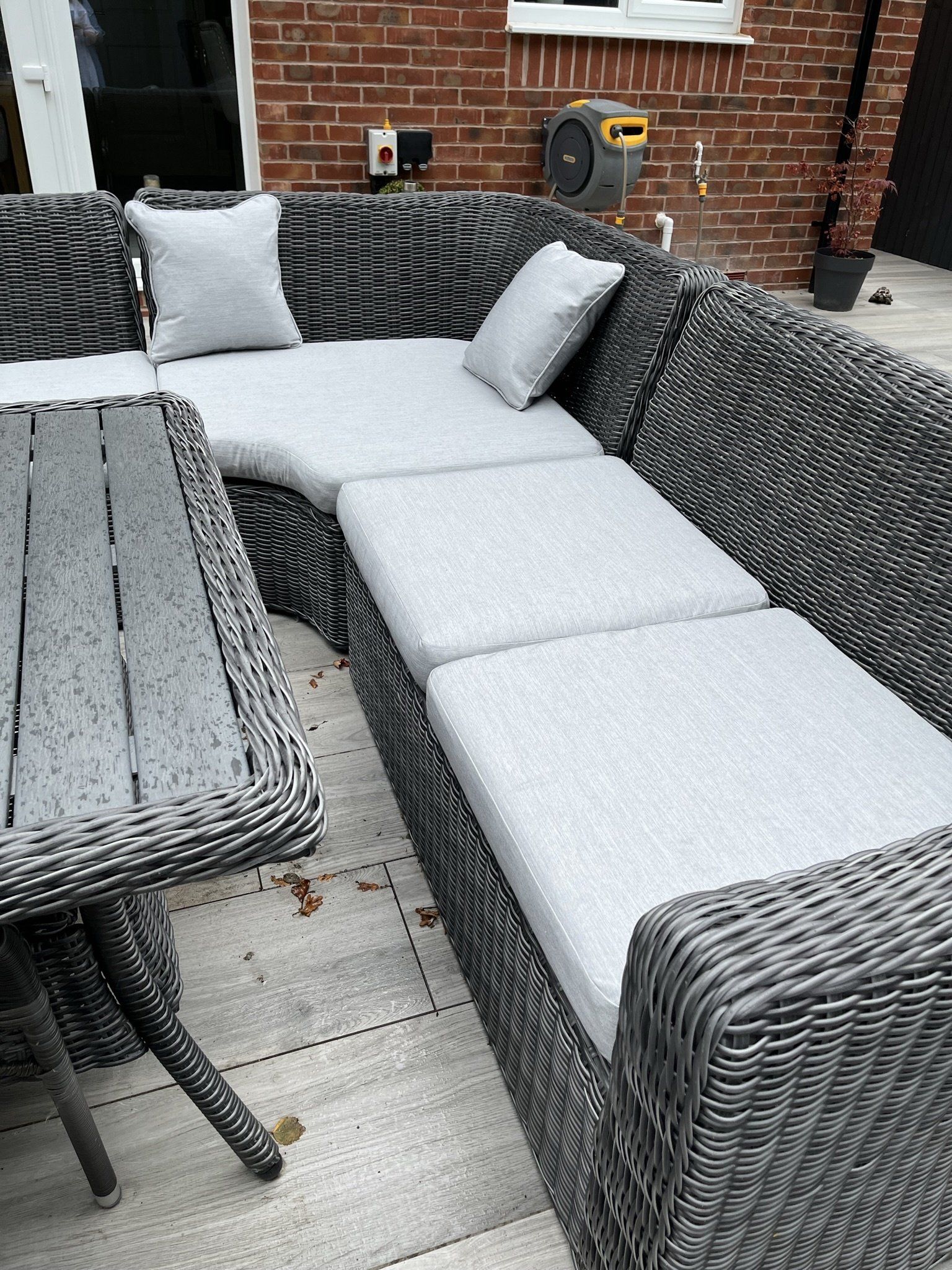 A wicker couch and table are sitting on a patio in front of a brick building.