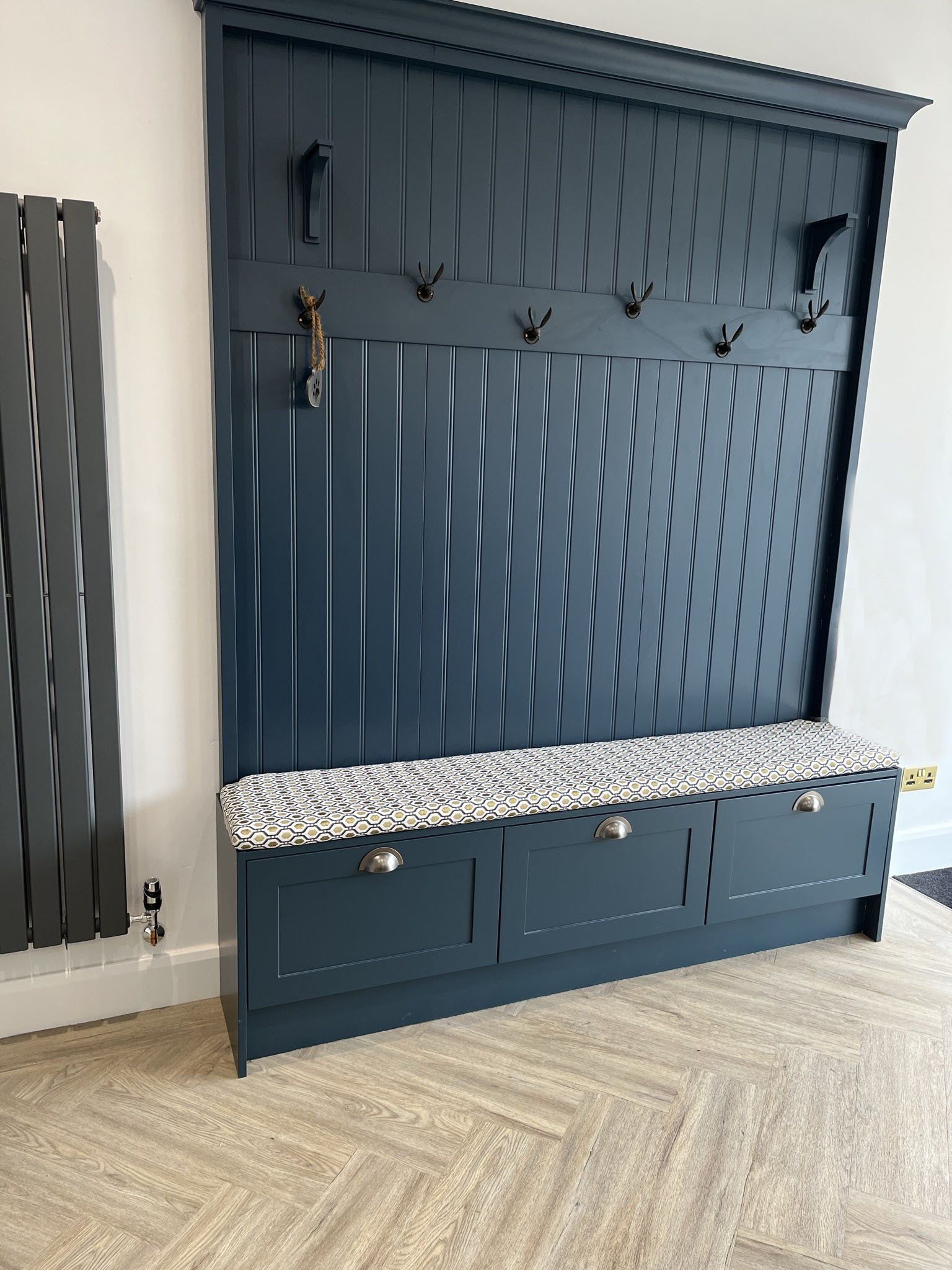 A hallway with a bench and a coat rack.
