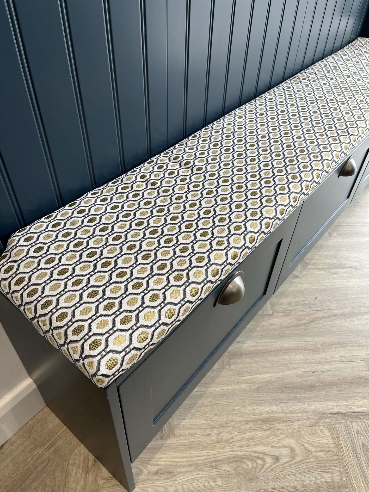 A bench with a pattern on it is sitting on a wooden floor.