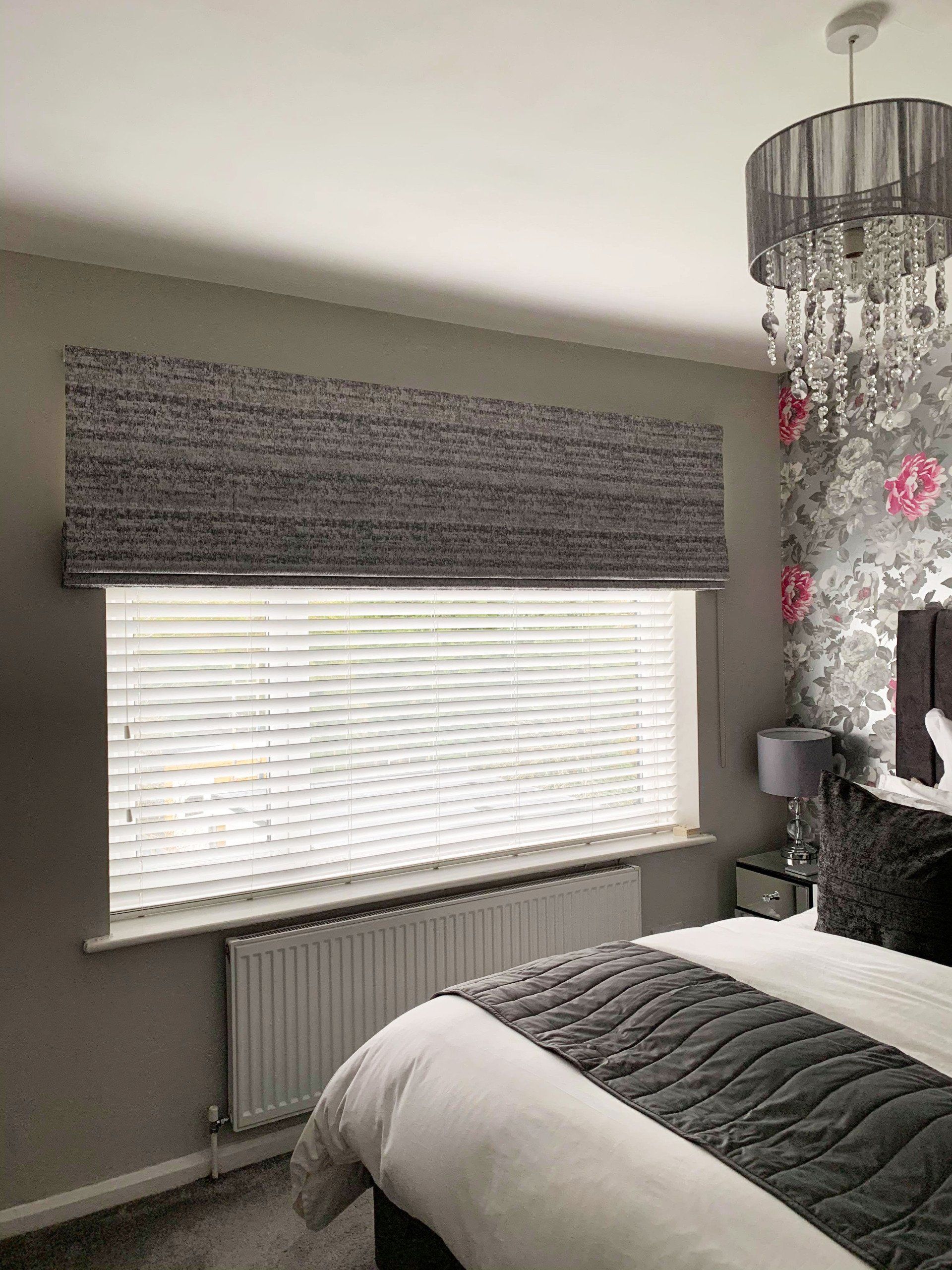 A bedroom with a bed , window , radiator and chandelier.