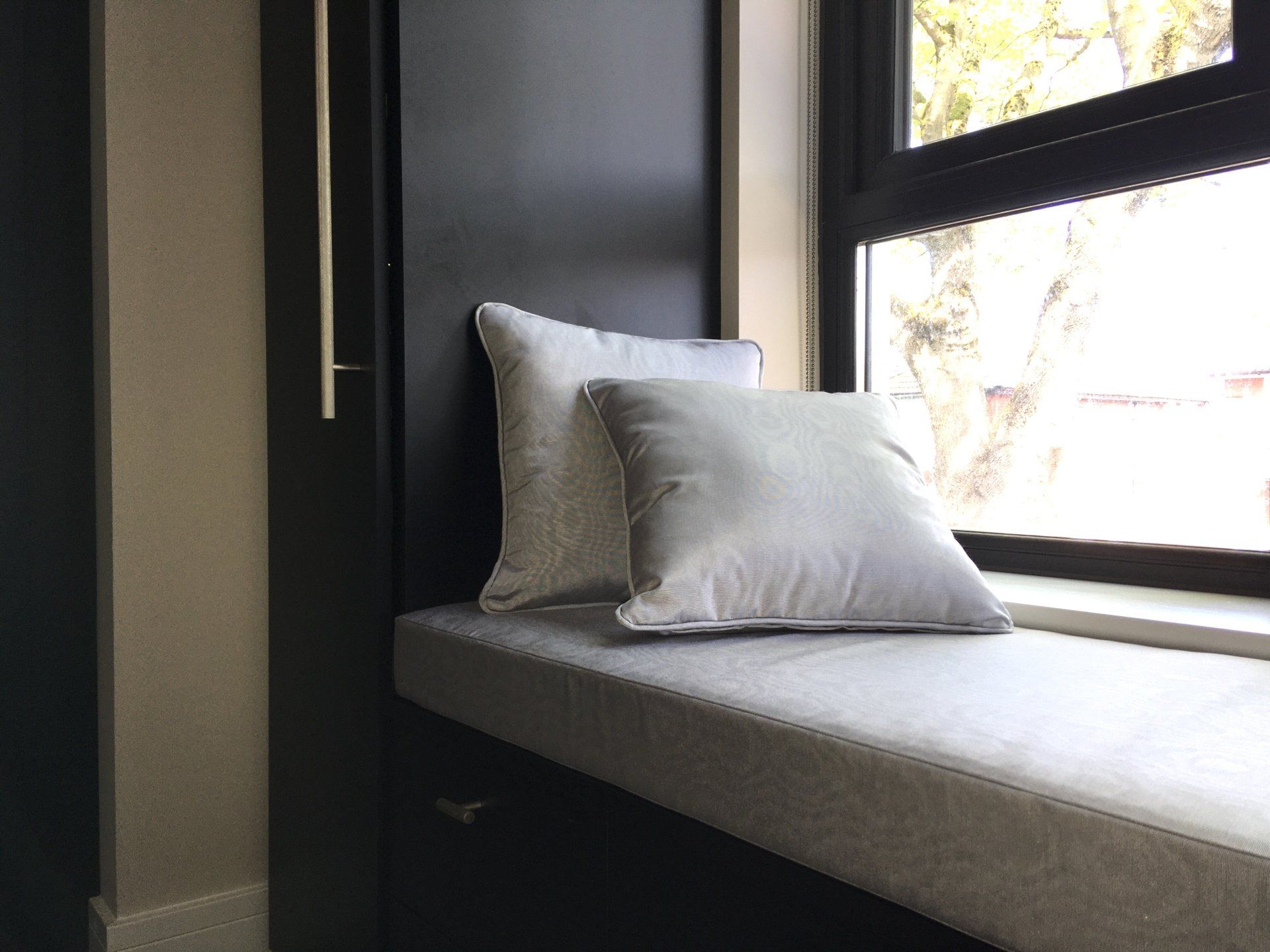 A window seat with two pillows on it next to a window.