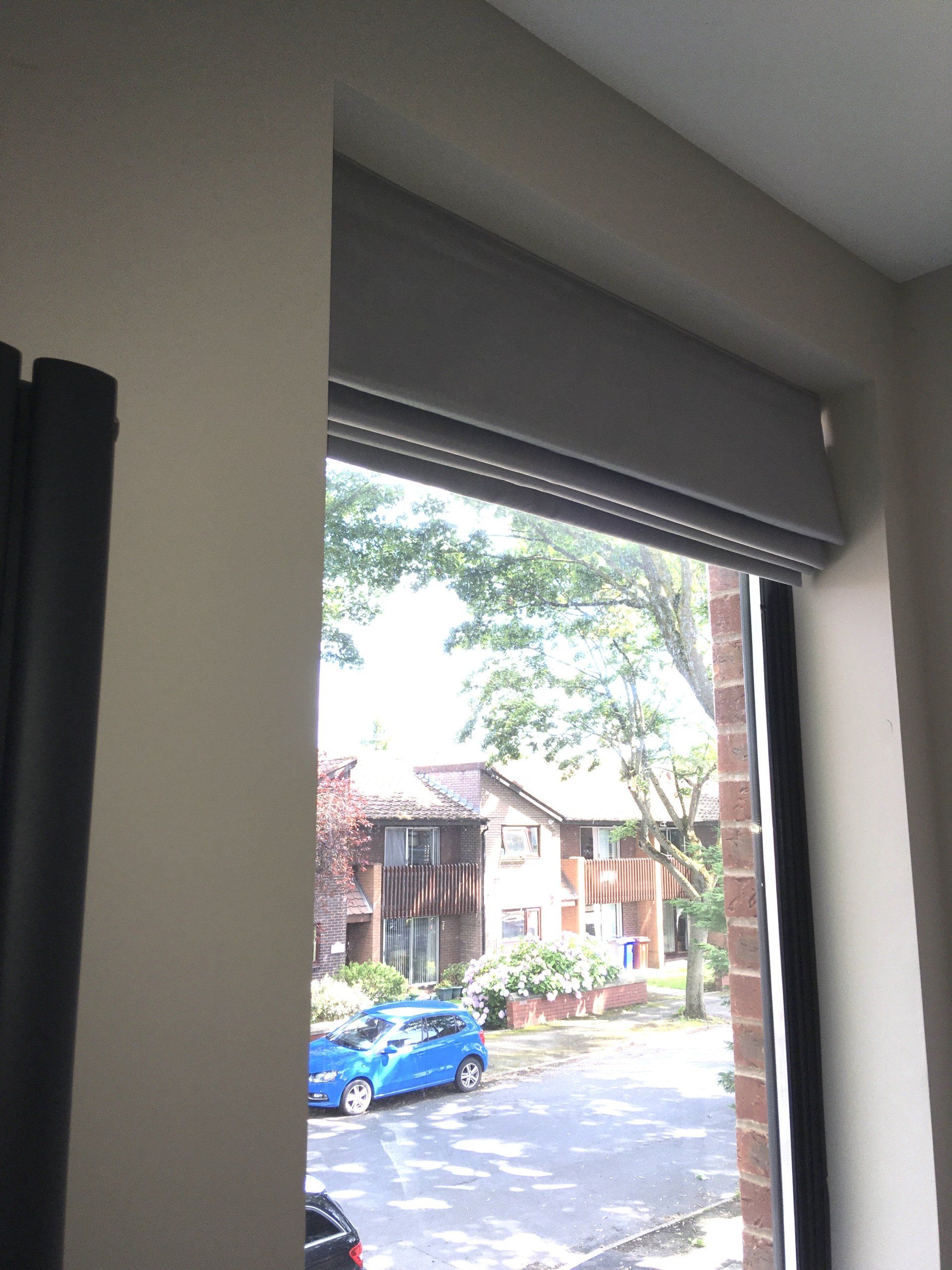 A blue car is parked in front of a window