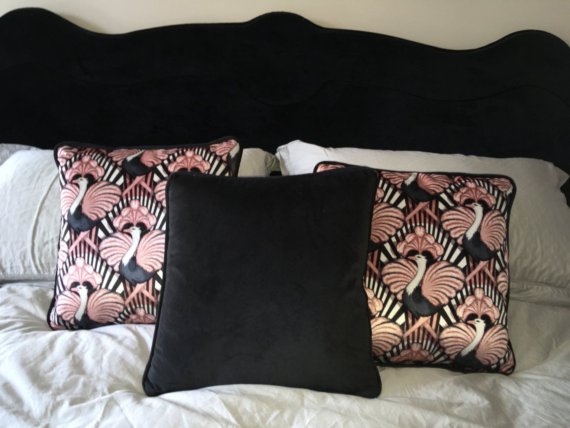 Three pillows on a bed with a black headboard