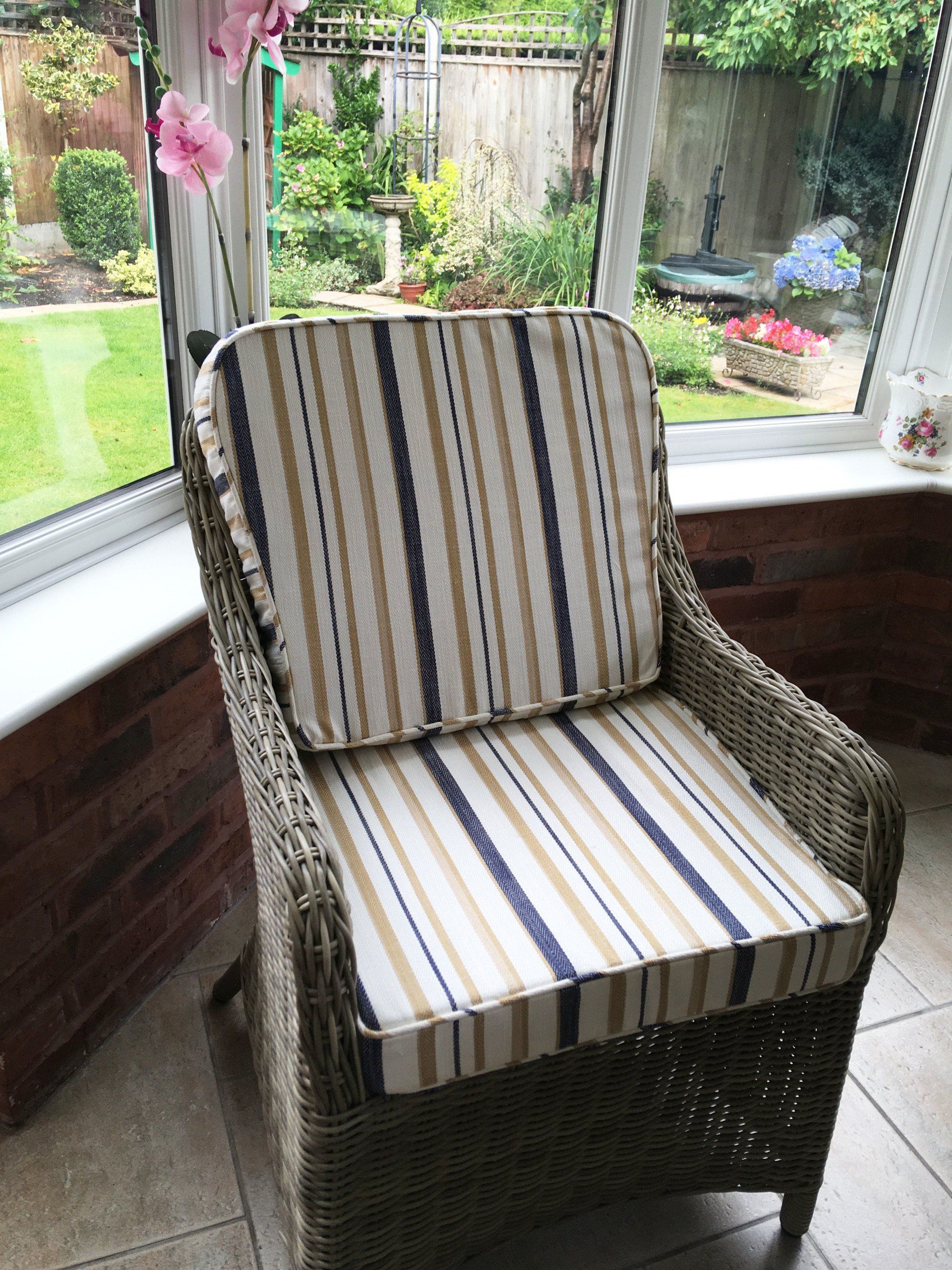 A wicker chair with a striped cushion is sitting in front of a window.