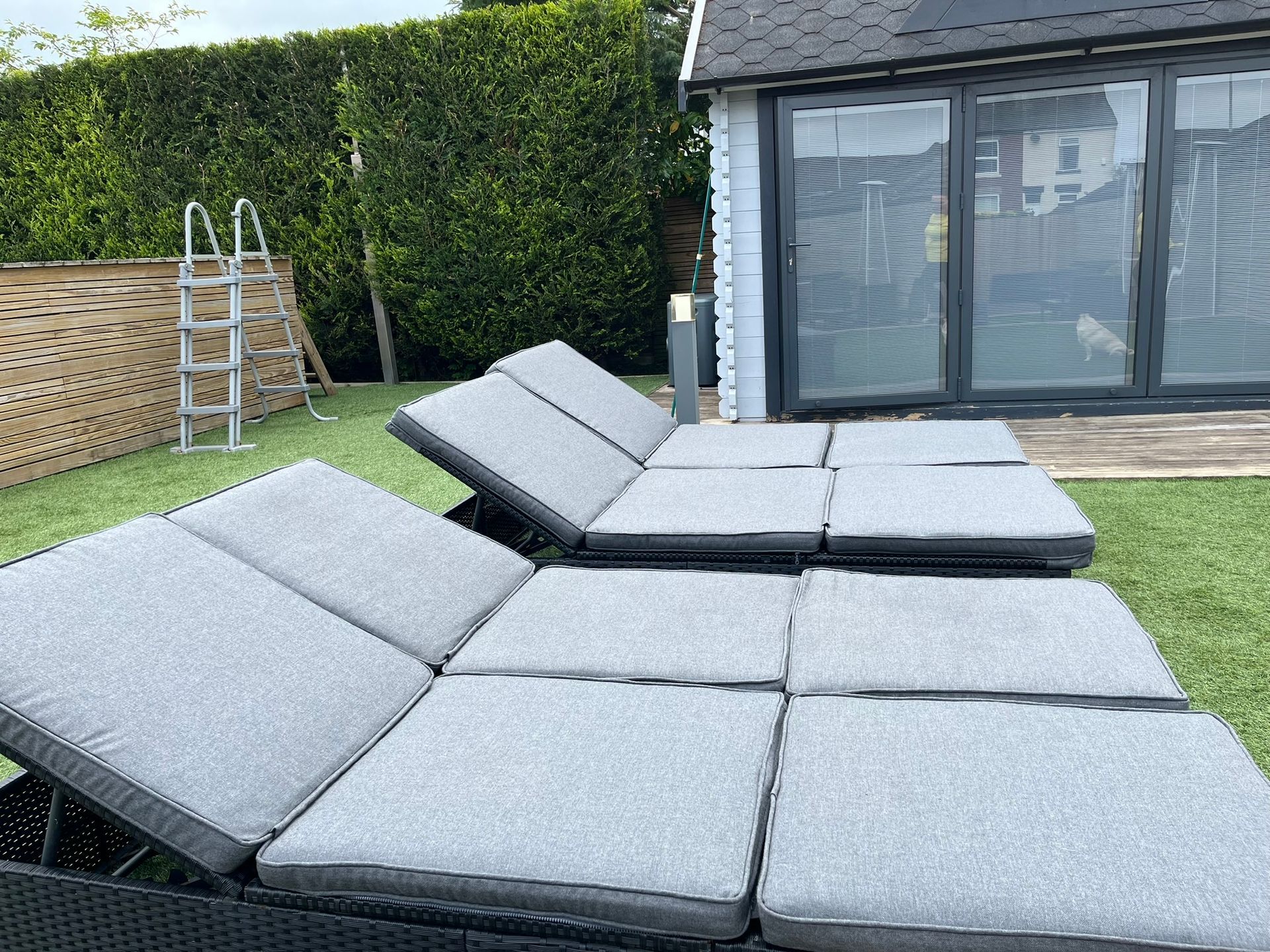 A row of lounge chairs in a backyard next to a pool.