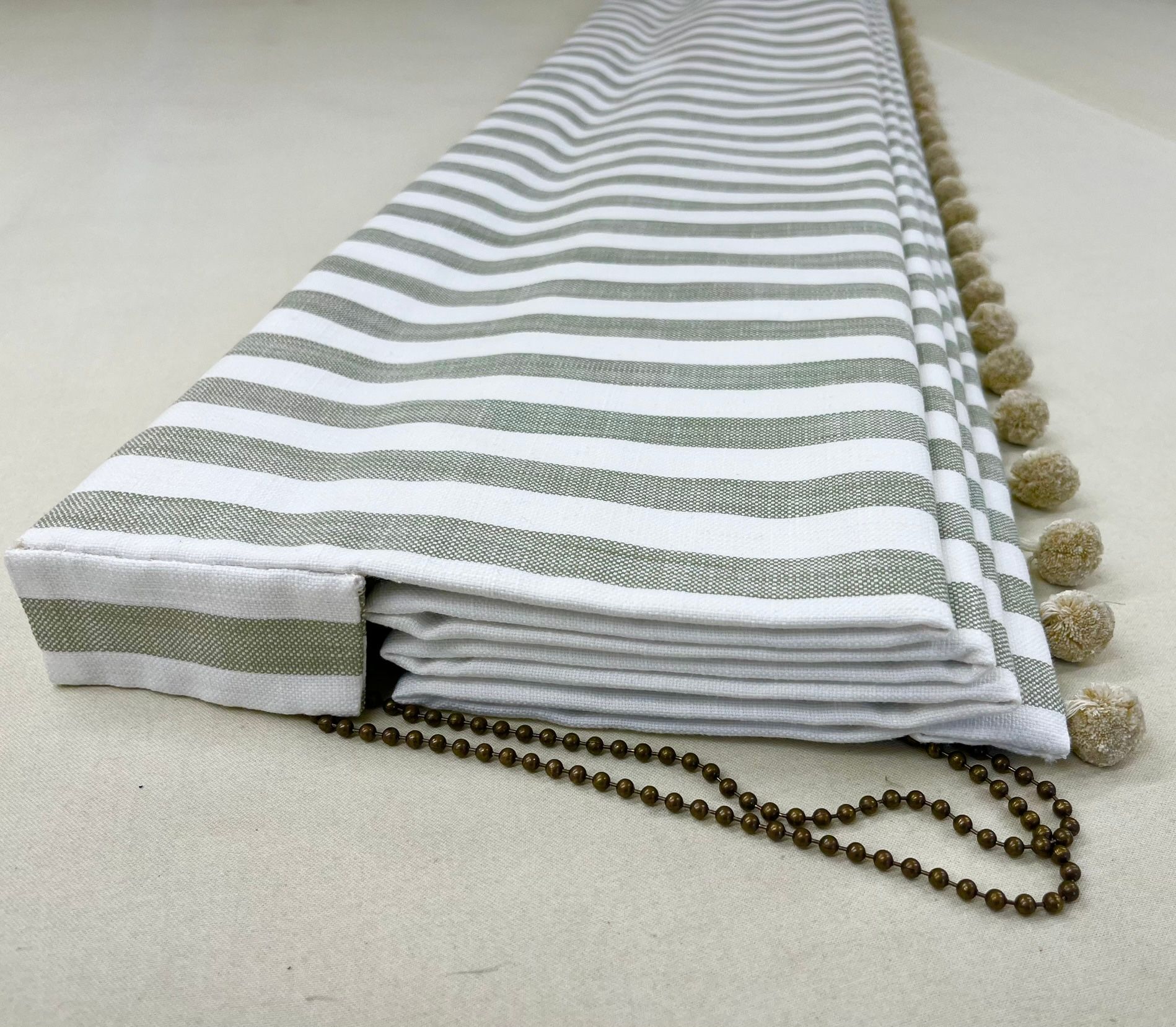 A striped curtain with a chain attached to it is sitting on a table.