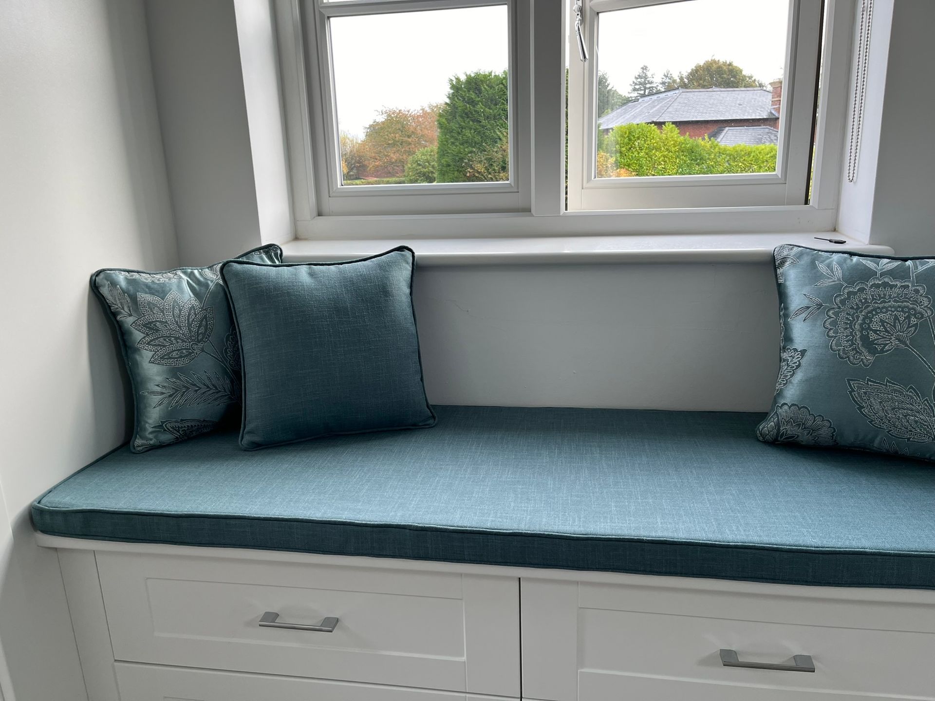 A window seat with a blue bench seat and two cushions