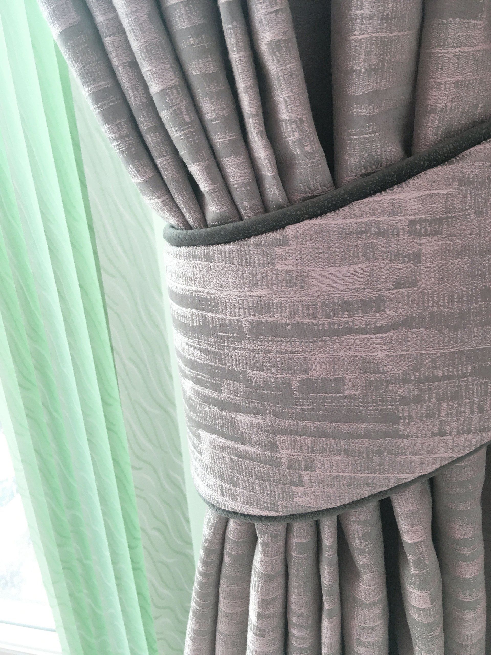 A close up of a pair of curtains hanging on a window.