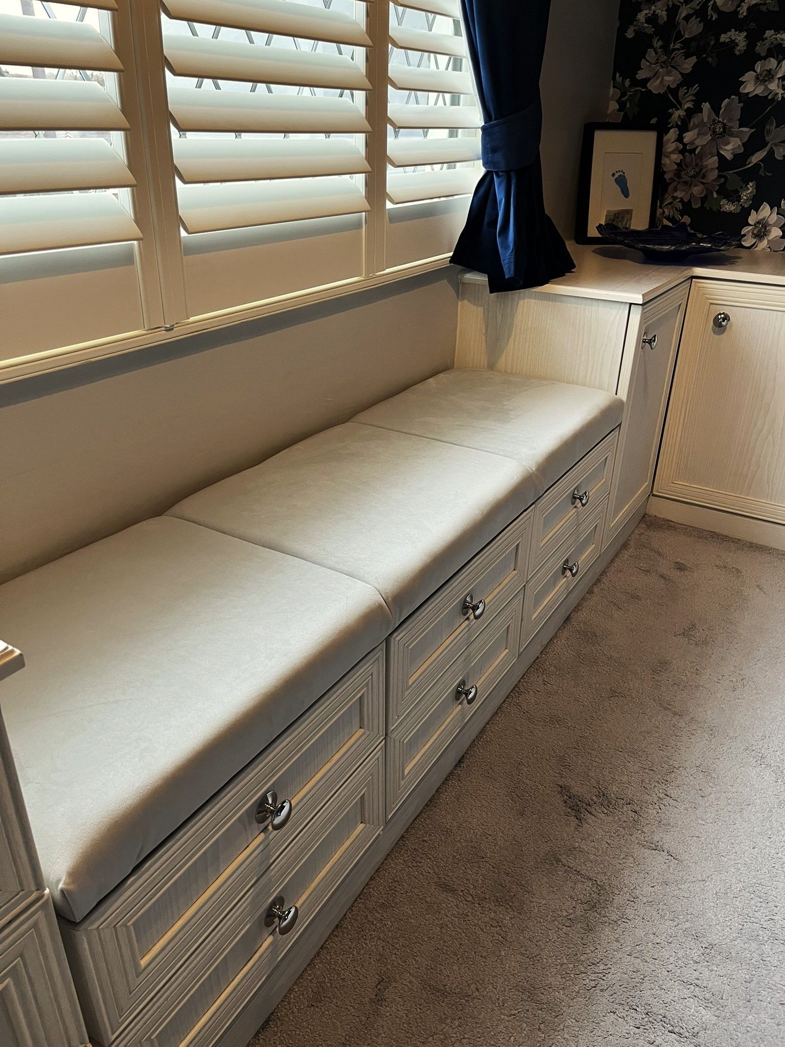 A bench with drawers underneath it in a room next to a window.