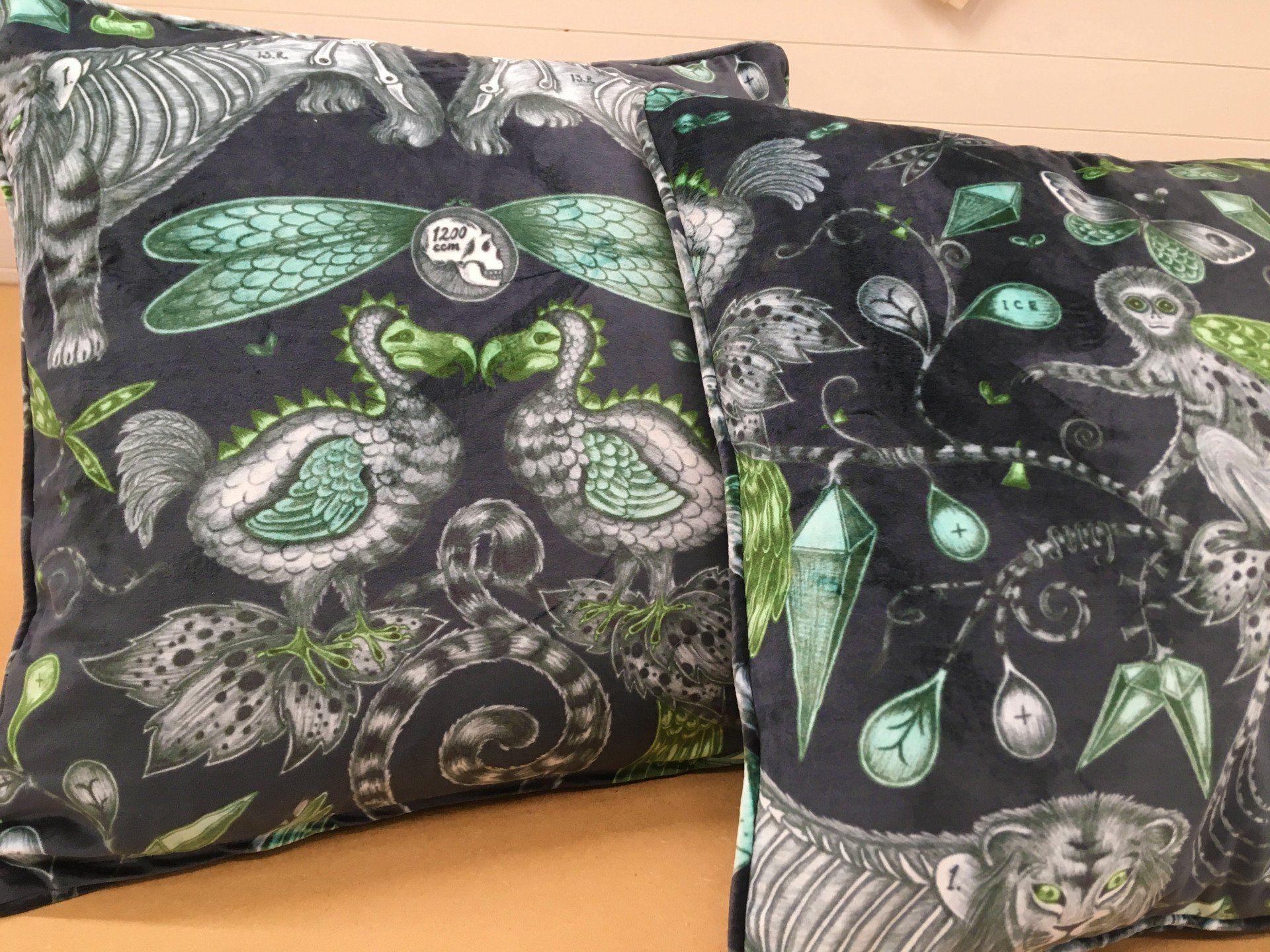 Two pillows with a dragonfly pattern on them are sitting on a wooden table.