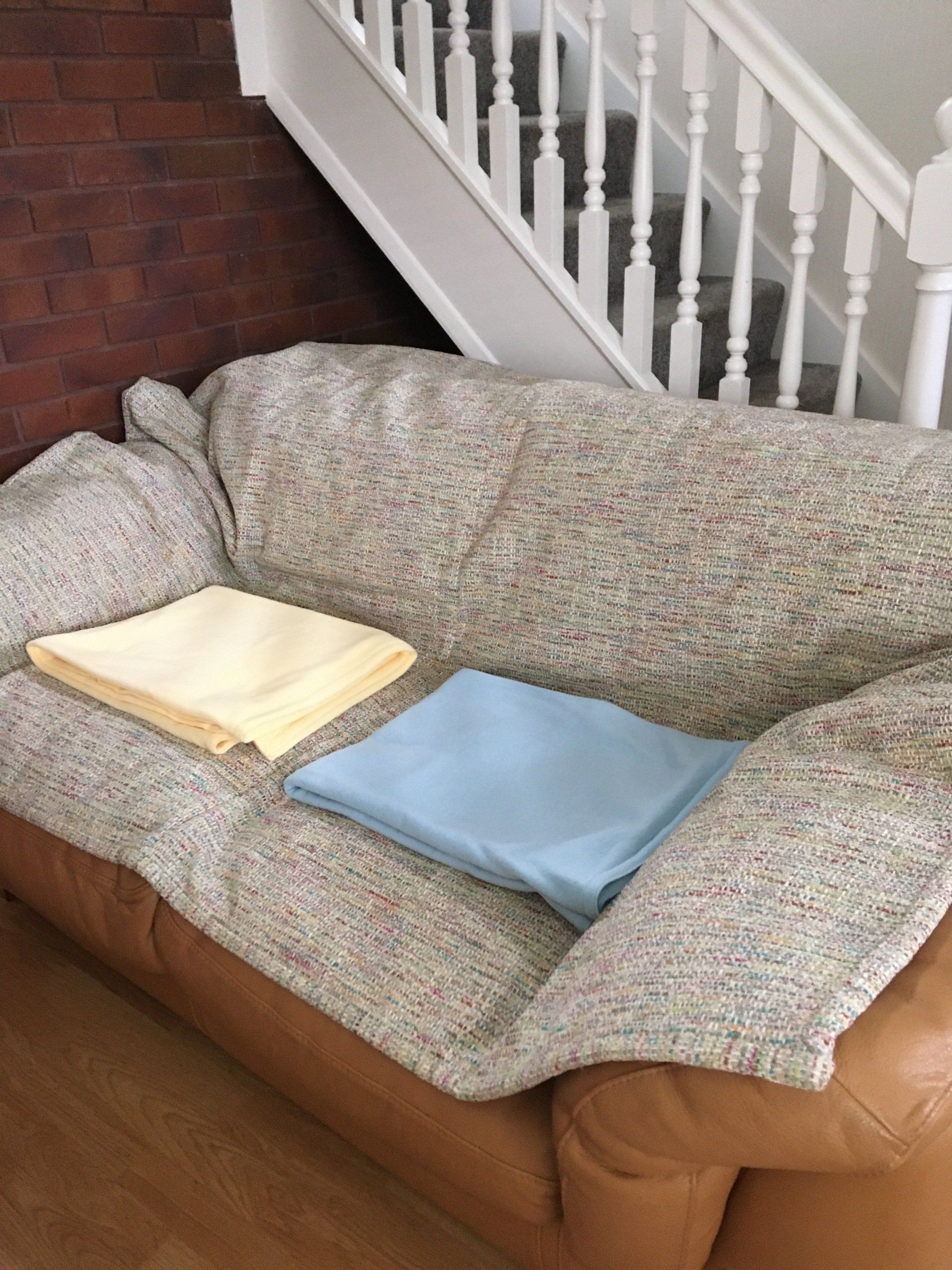 Two blankets are sitting on a couch next to a staircase.
