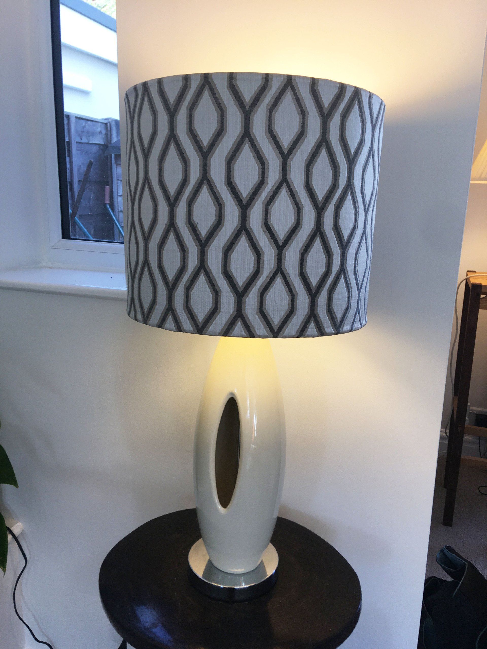 A lamp with a patterned shade is sitting on a table.