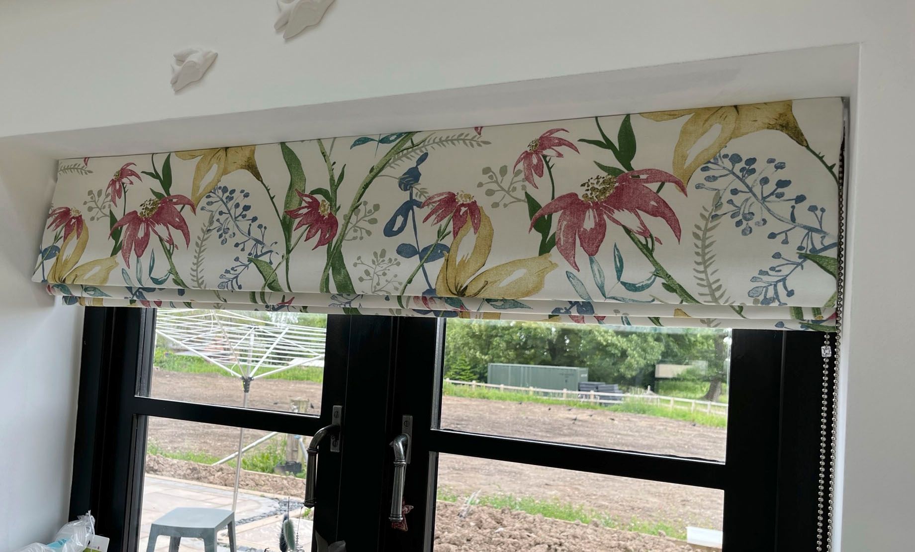 A window with a roman shade and a floral pattern on it.