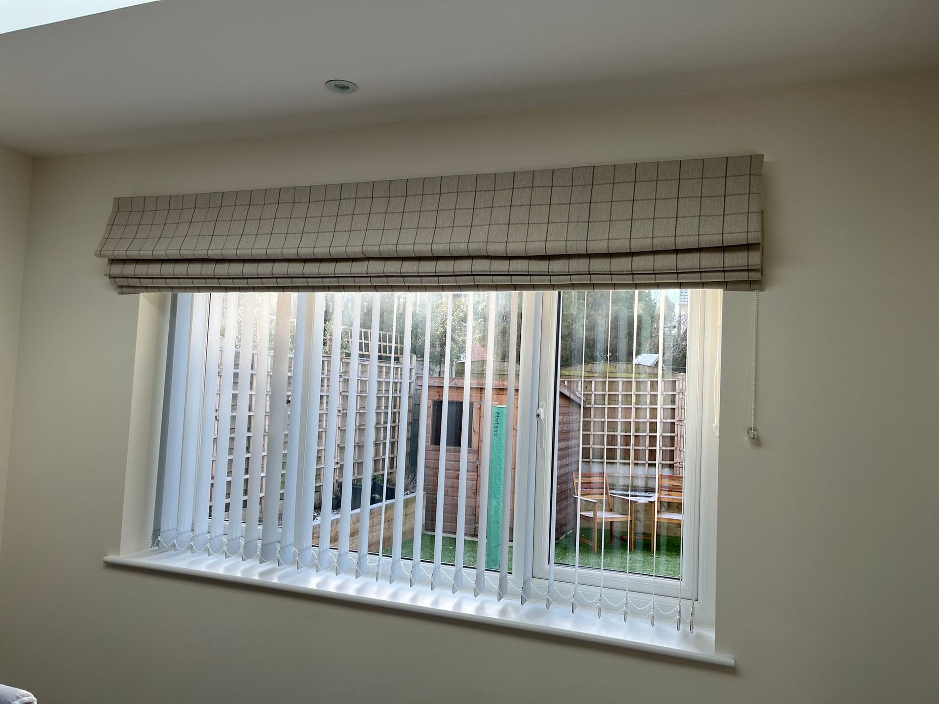 A window with vertical blinds and a roman shade