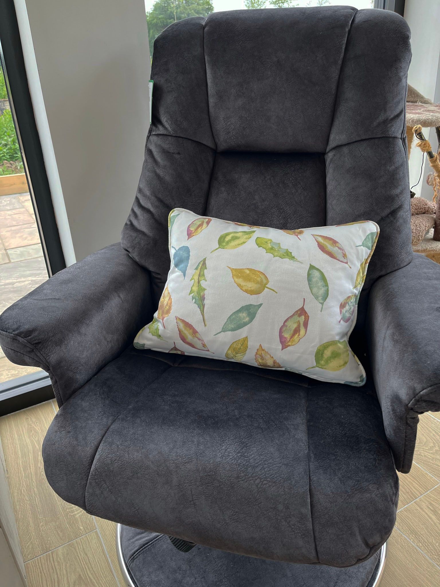 A chair with a pillow on it is sitting in front of a window.