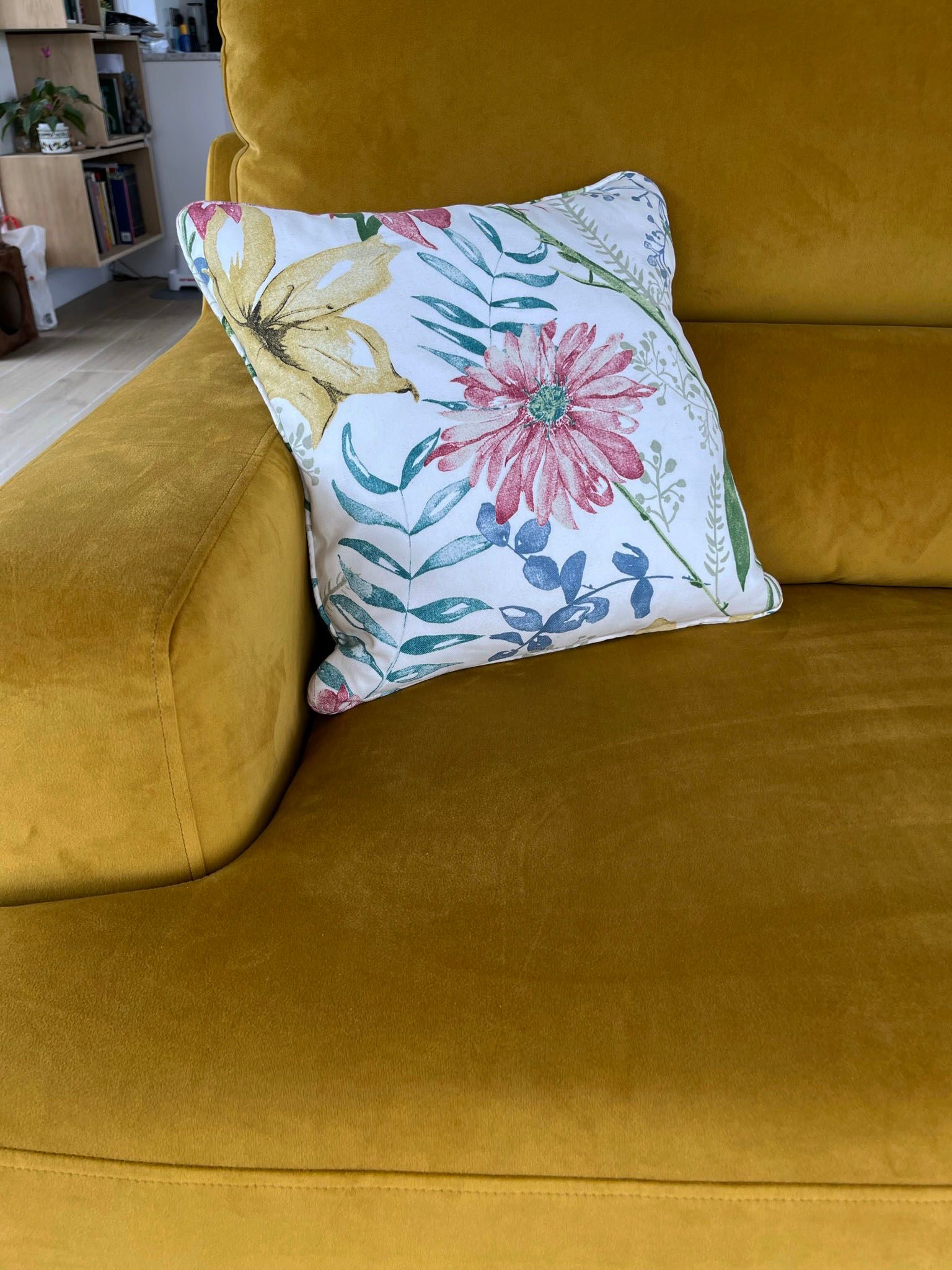 A yellow couch with a floral pillow on it
