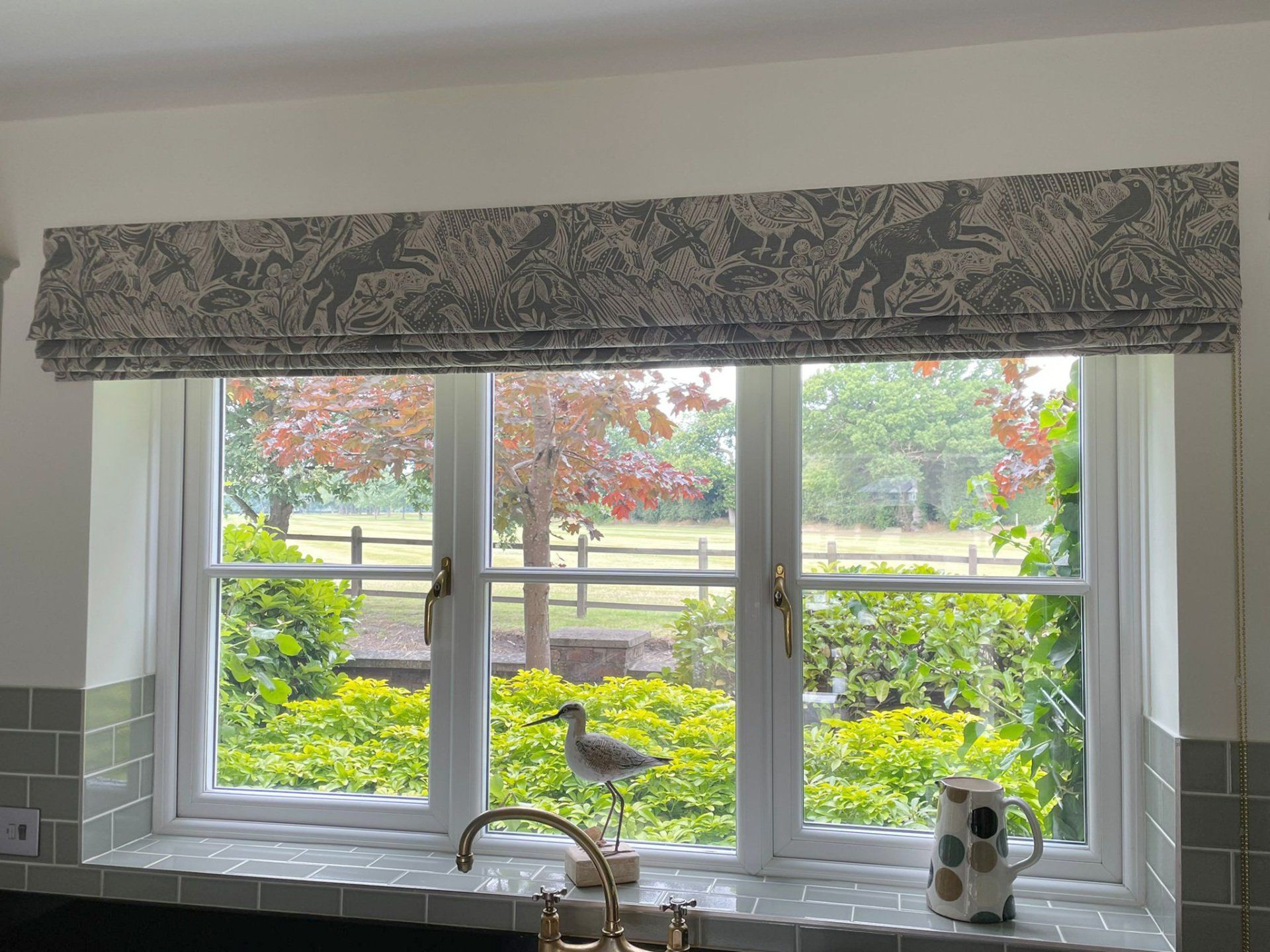 A bird is sitting on a window sill in a kitchen.