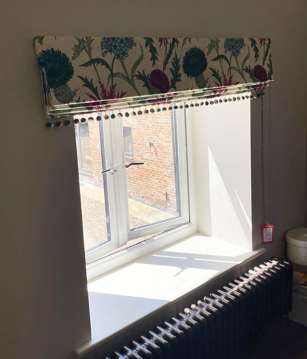 A window with a floral blind and a radiator underneath it