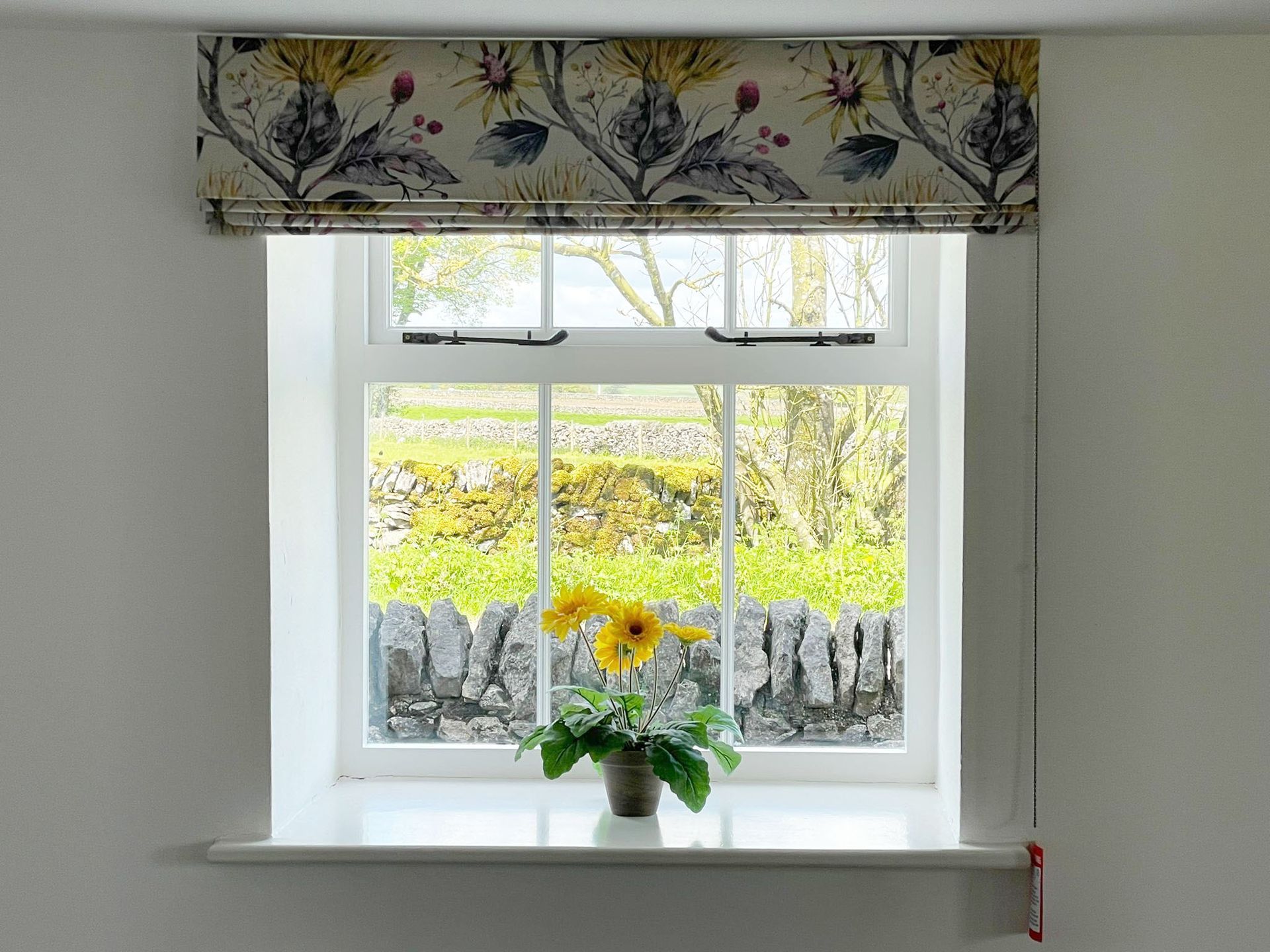 A window with a vase of flowers on the window sill.
