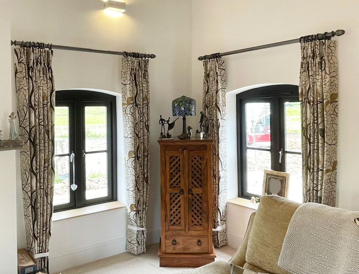 A living room with a couch , cabinet , and two windows.