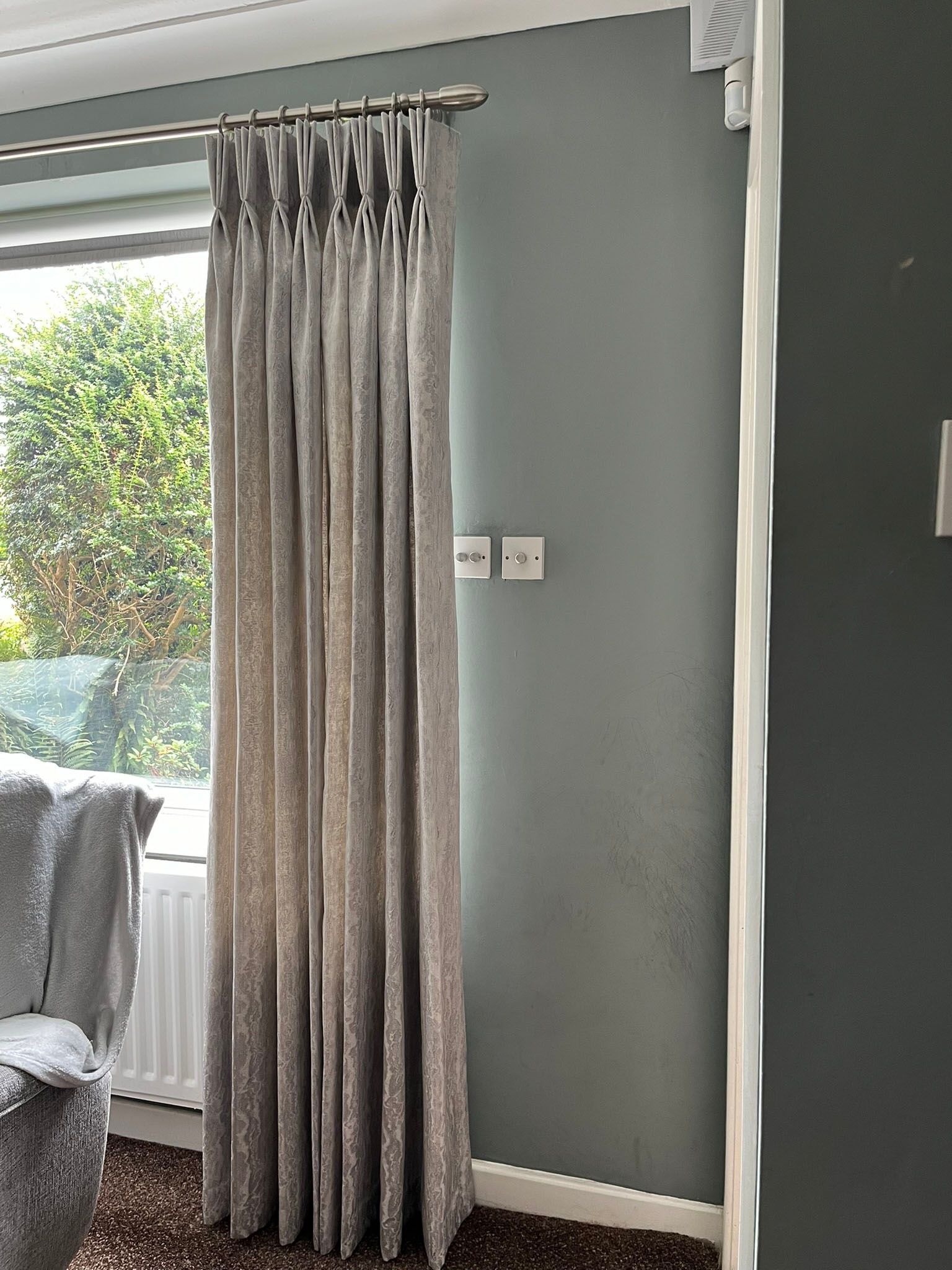 A living room with a chair and a window with curtains on it.