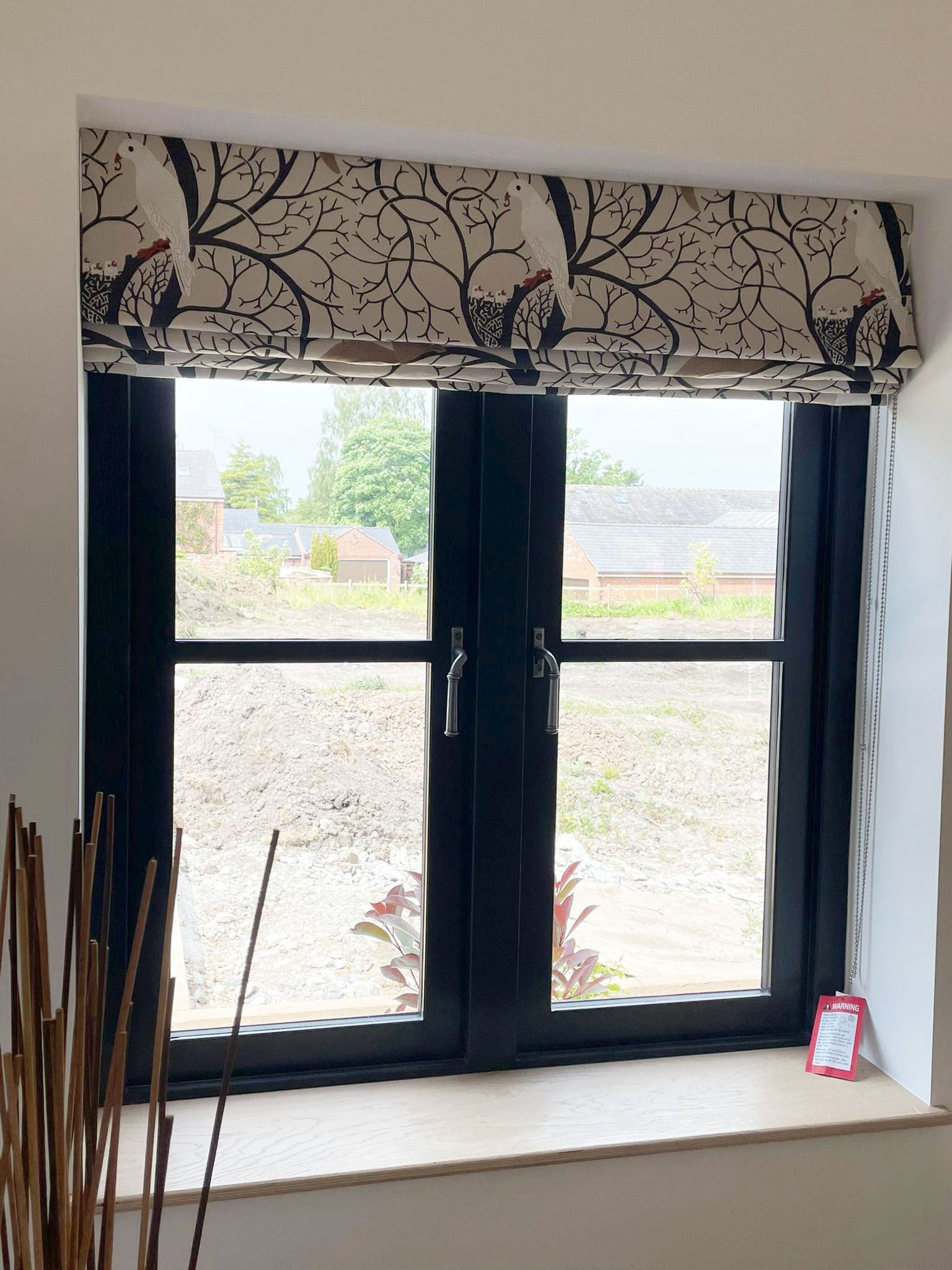 A window with a black frame and a roman shade on it.