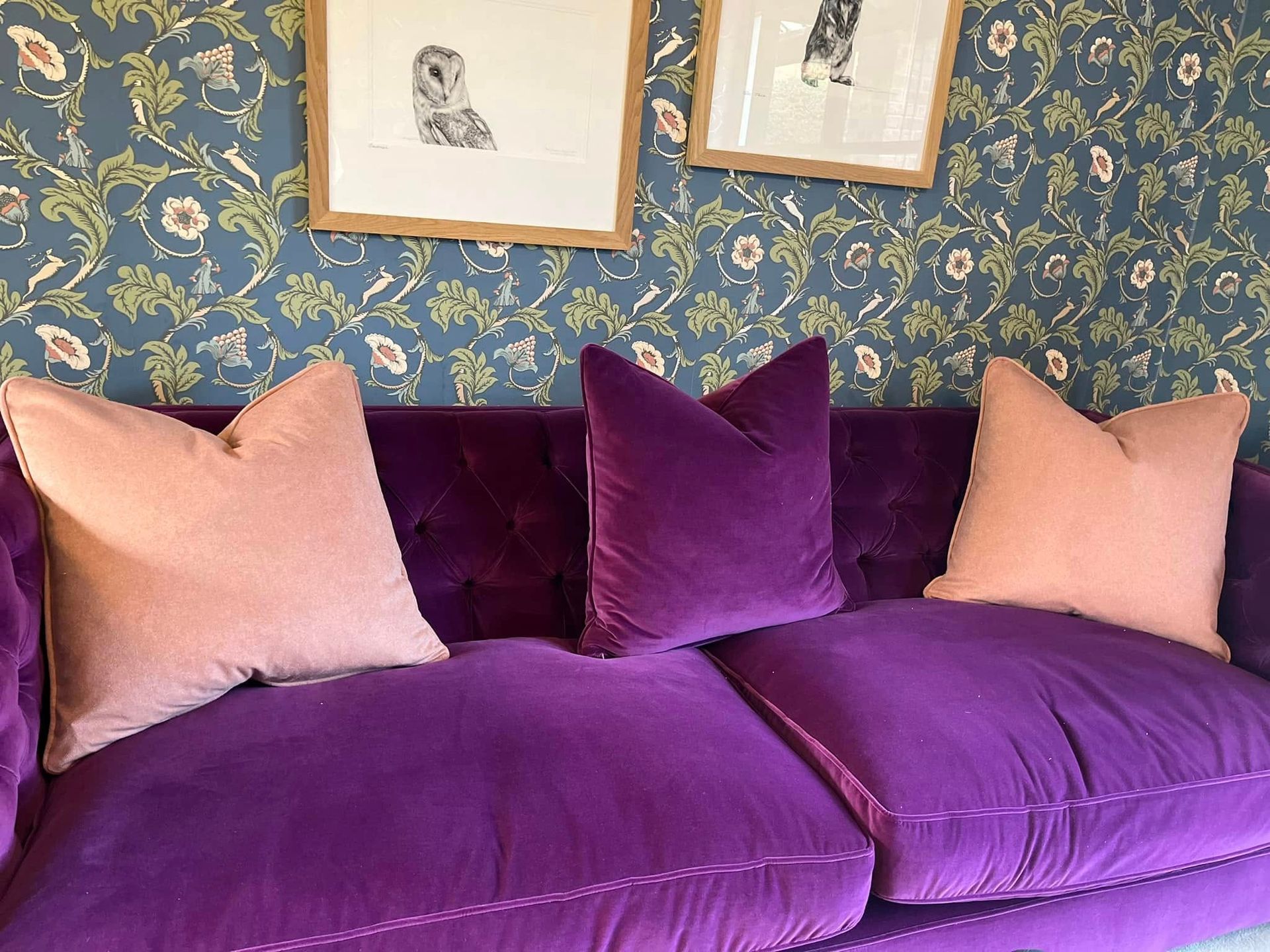 A purple couch with pink pillows in a living room.